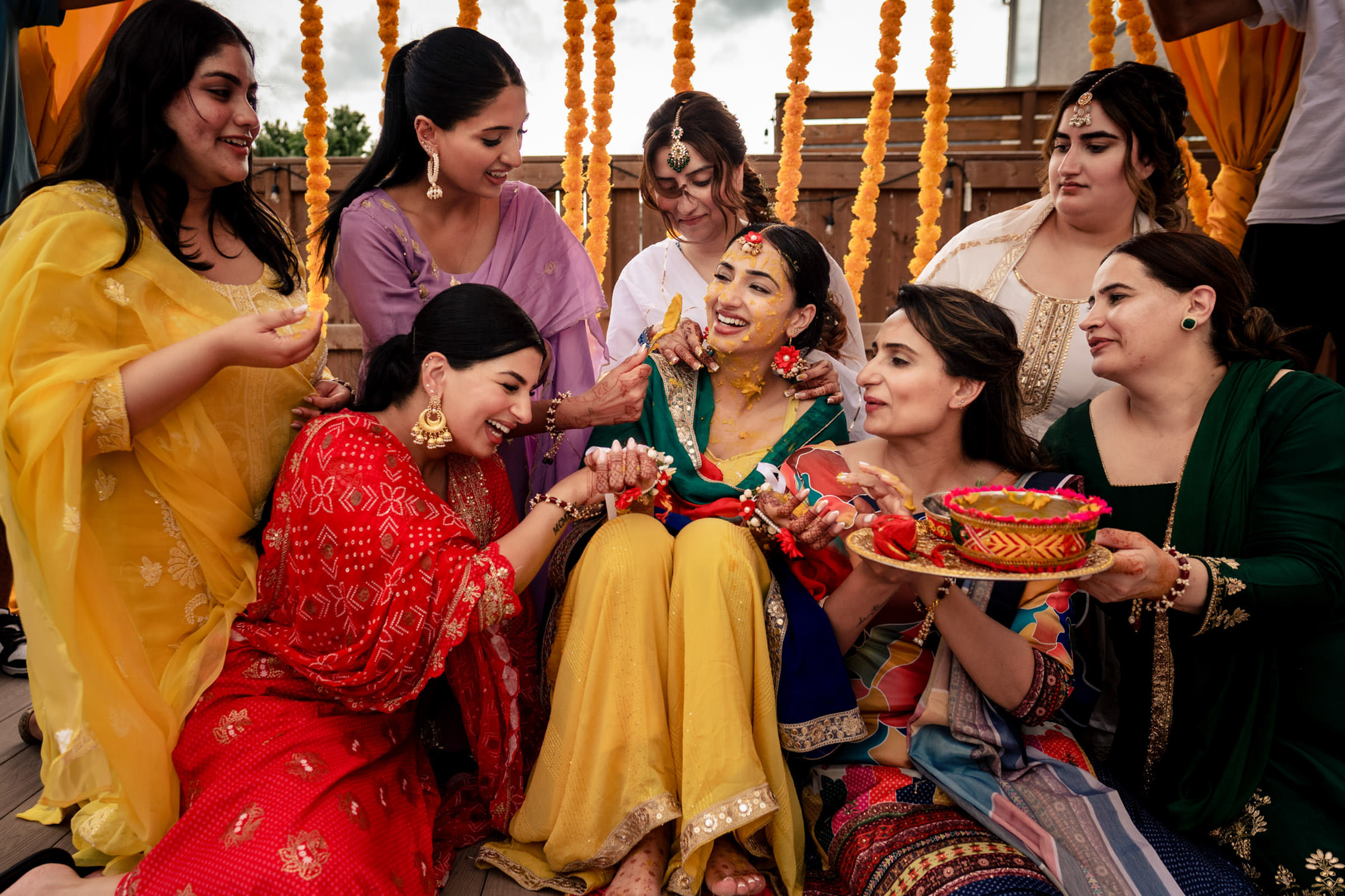 A group of women celebrating with a bride covered in turmeric at a Winnipeg wedding.