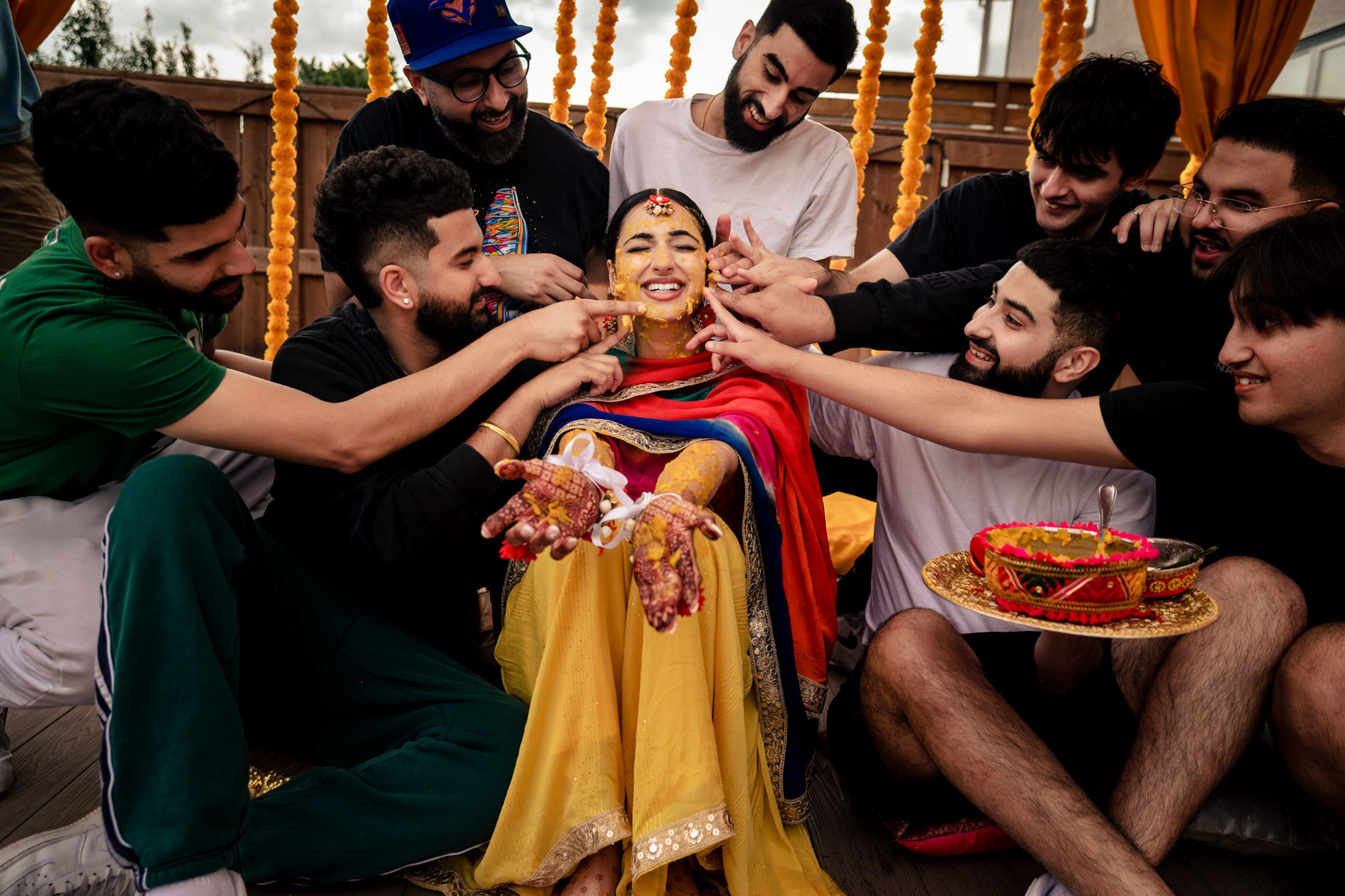 Bride in festive attire is surrounded by smiling friends at a Winnipeg wedding celebration.