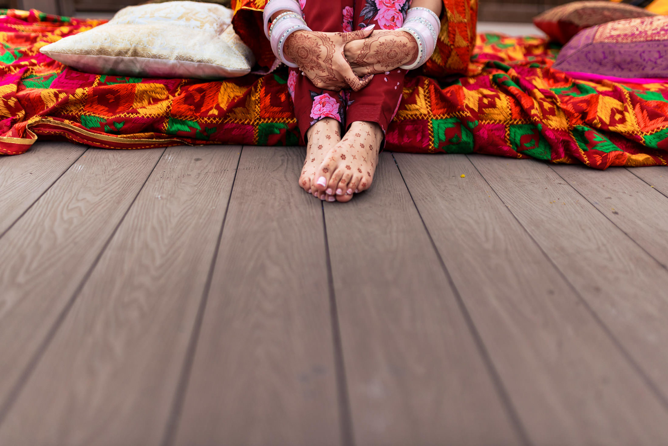Person in traditional attire with henna, seated on colorful fabric at a Winnipeg wedding.
