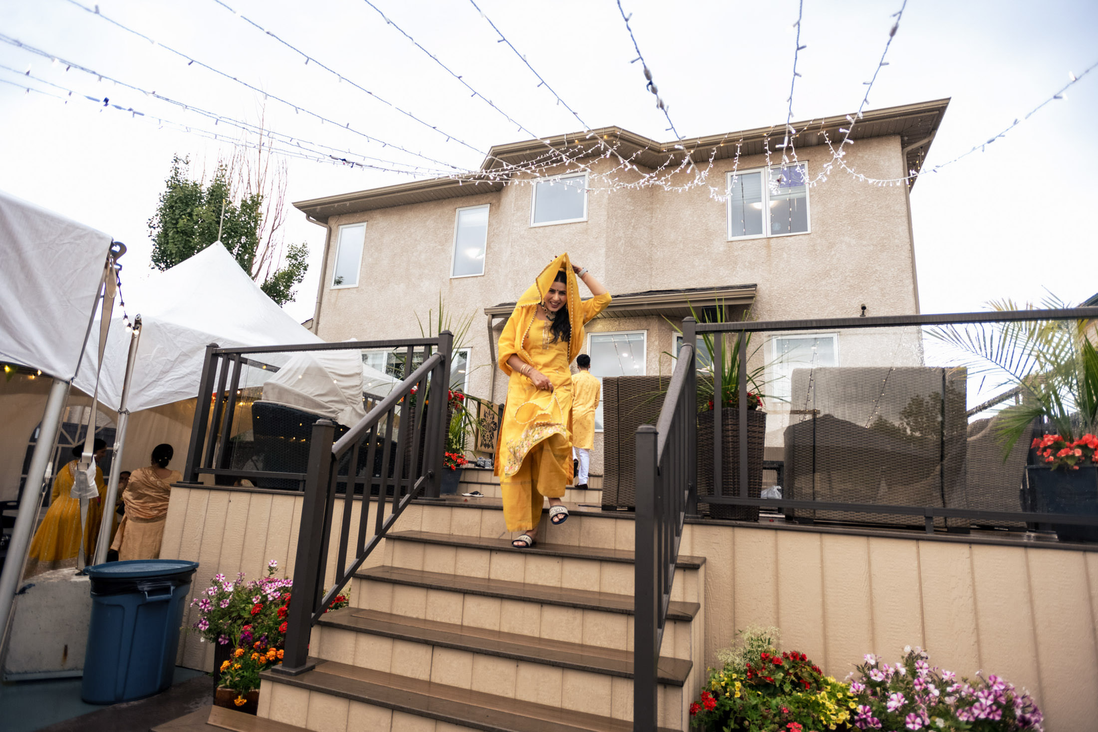 Person in yellow outfit walking down steps at Winnipeg wedding with string lights and tents.