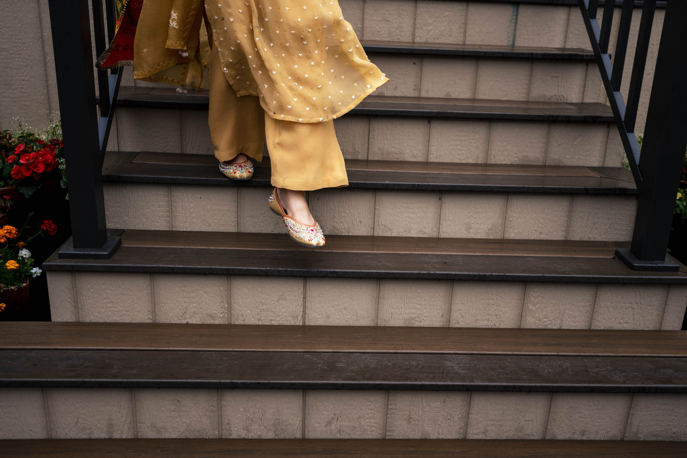 Person in a golden outfit descending stairs at a Winnipeg wedding, wearing decorated shoes.