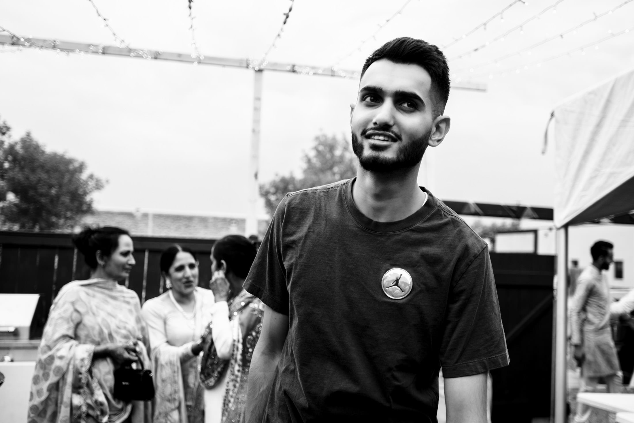 Man smiling outdoors, with a Winnipeg wedding party in the background.