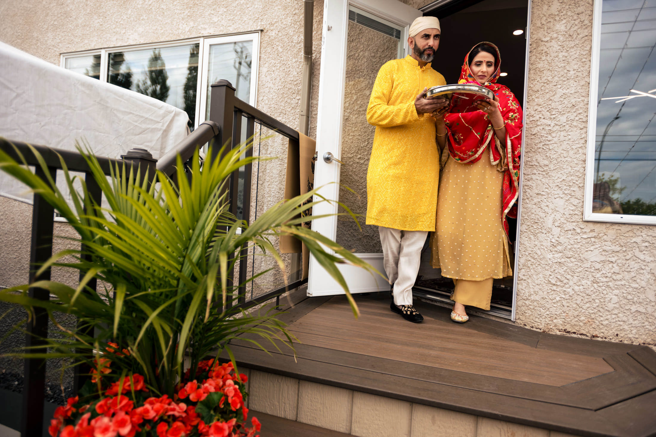 A couple in traditional attire steps out, holding a tray at a Winnipeg wedding.
