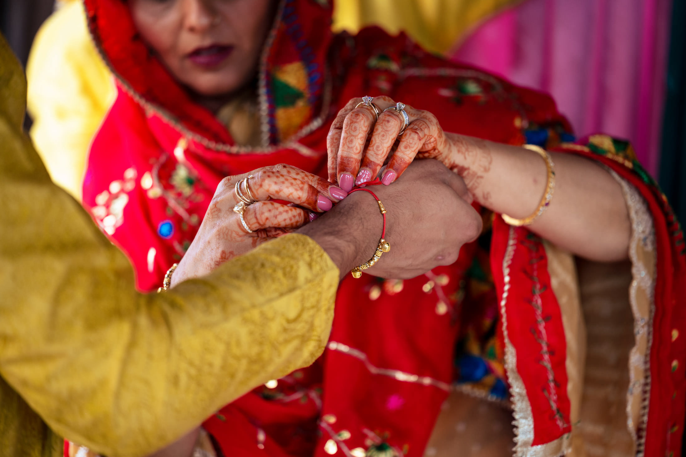 Close-up of jewelry being placed on henna-adorned hands at a Winnipeg wedding.