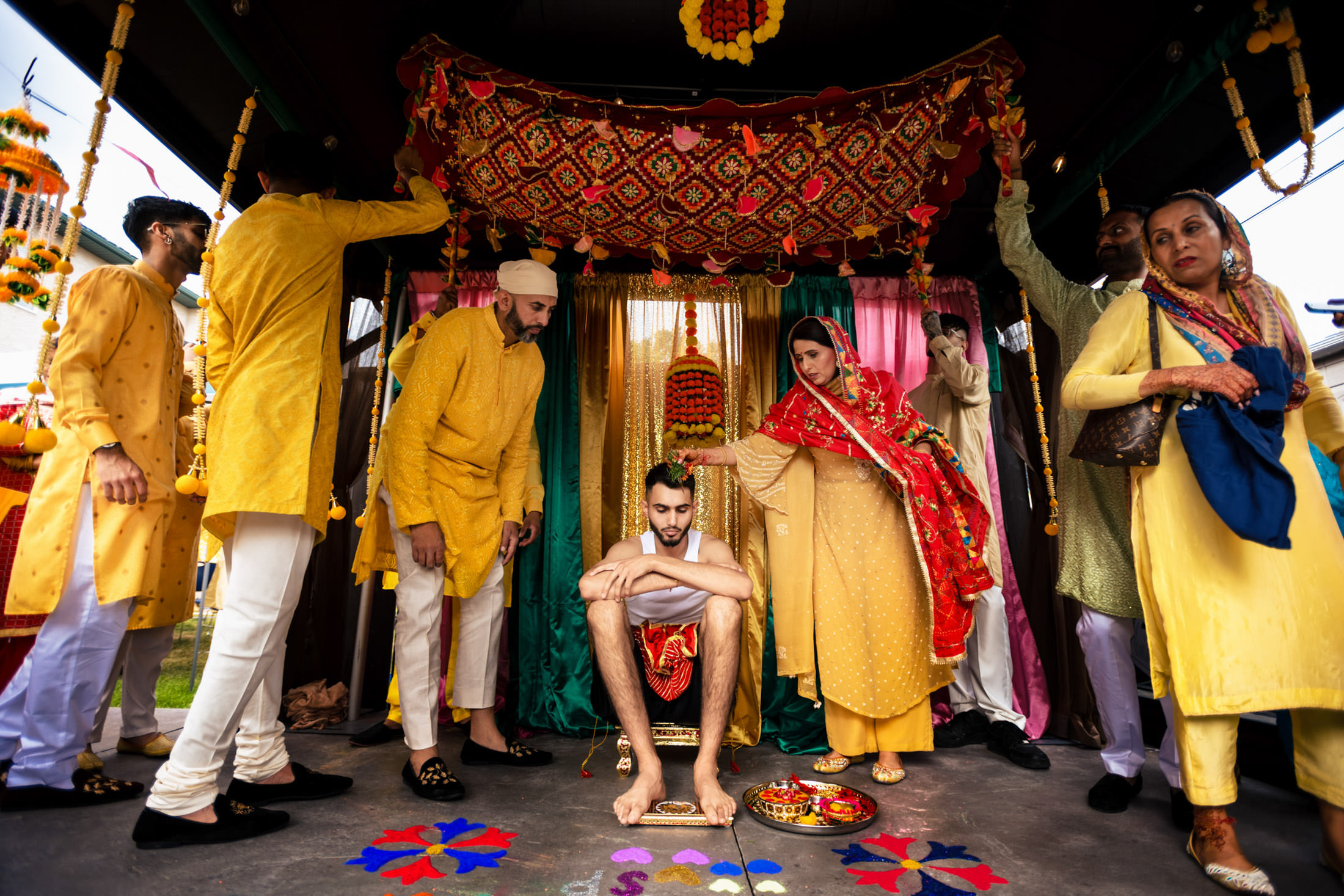 Vibrant attire surrounds a seated person at a colorful Winnipeg wedding ceremony.