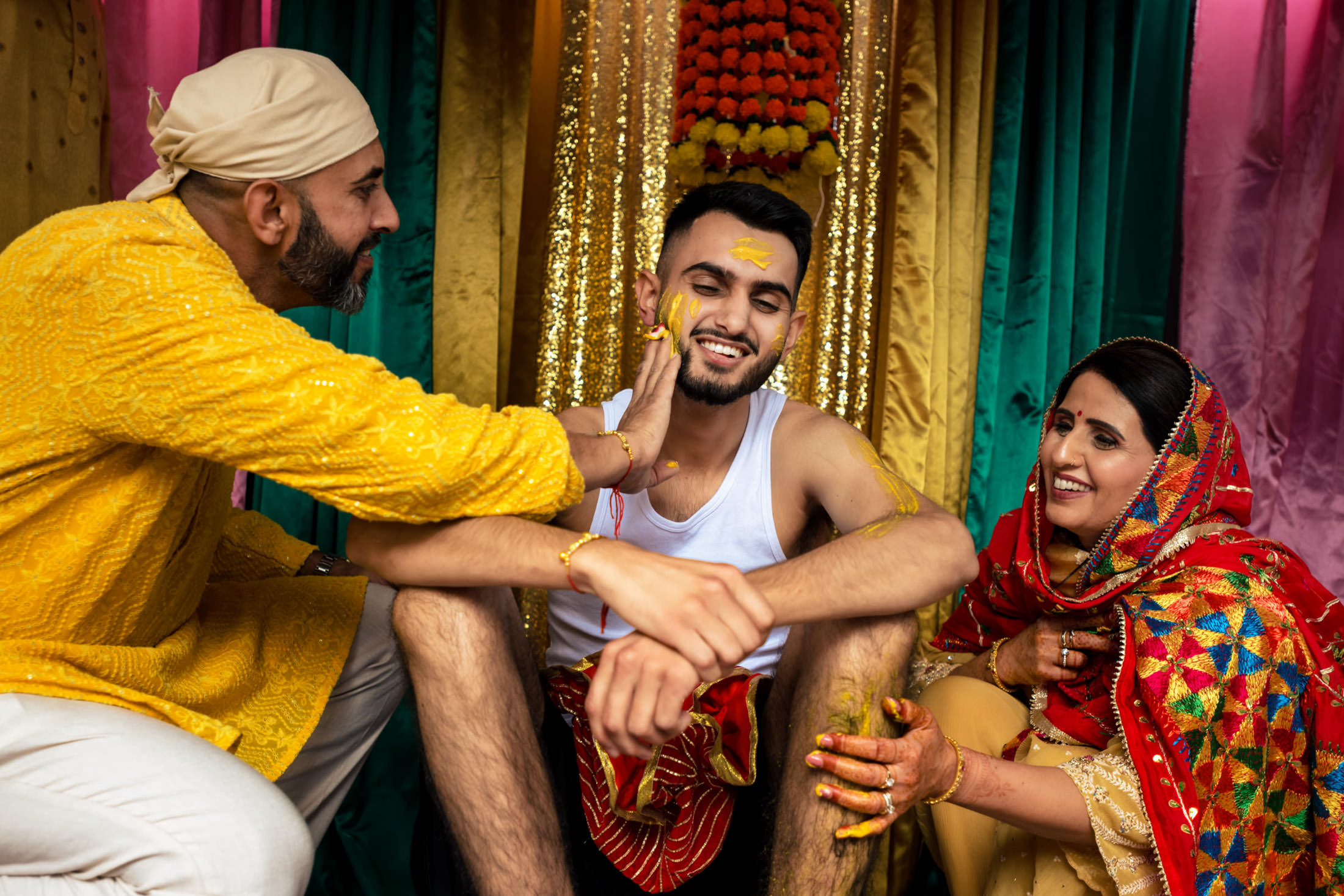 Three people at a vibrant, joyful Winnipeg wedding with colorful drapes and floral decor.