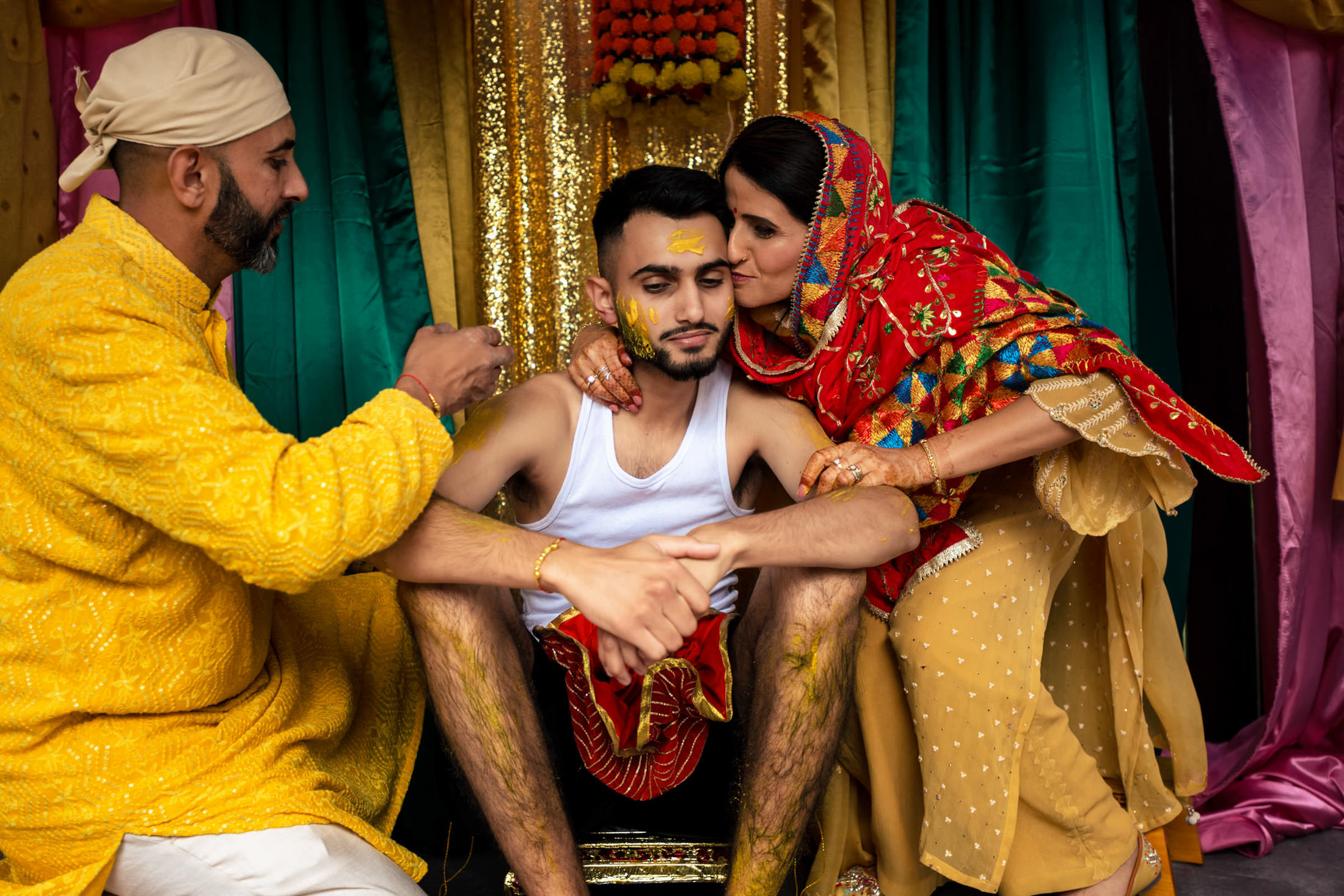 Traditional Winnipeg wedding with a man receiving blessings from elders in vibrant clothes.
