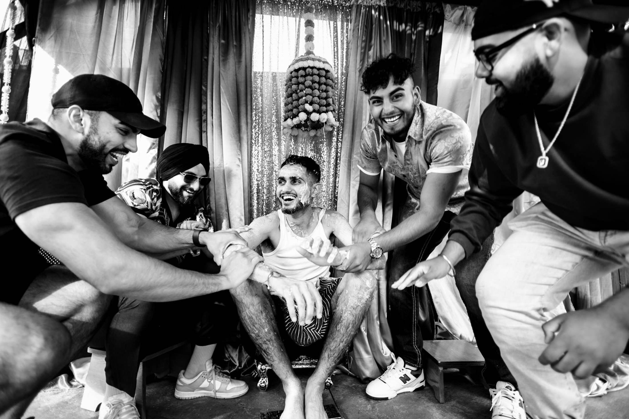 Five men laughing and celebrating together at a lively Winnipeg wedding, in black and white.