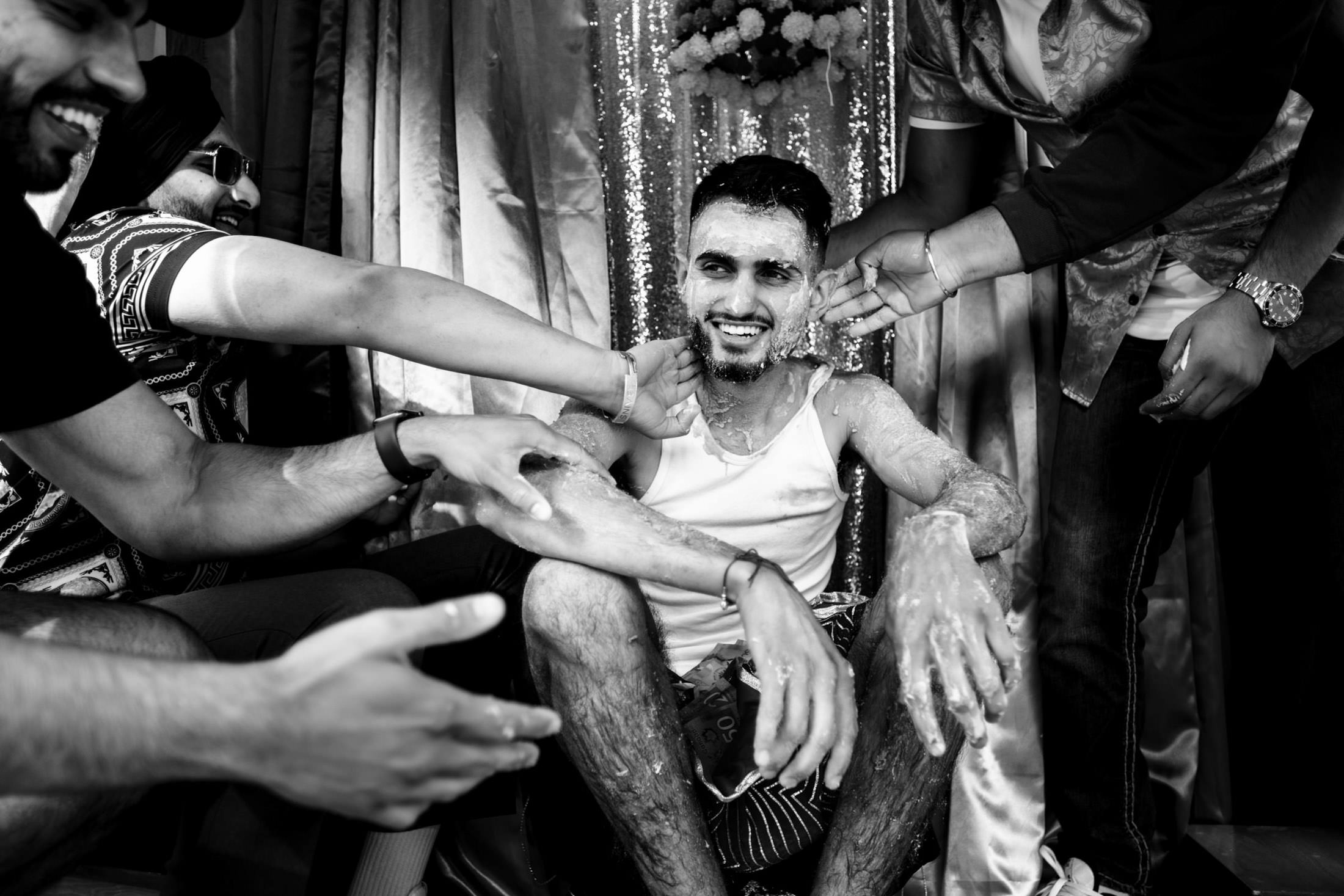 In a joyous Winnipeg wedding, a man is covered in cream by cheerful friends.