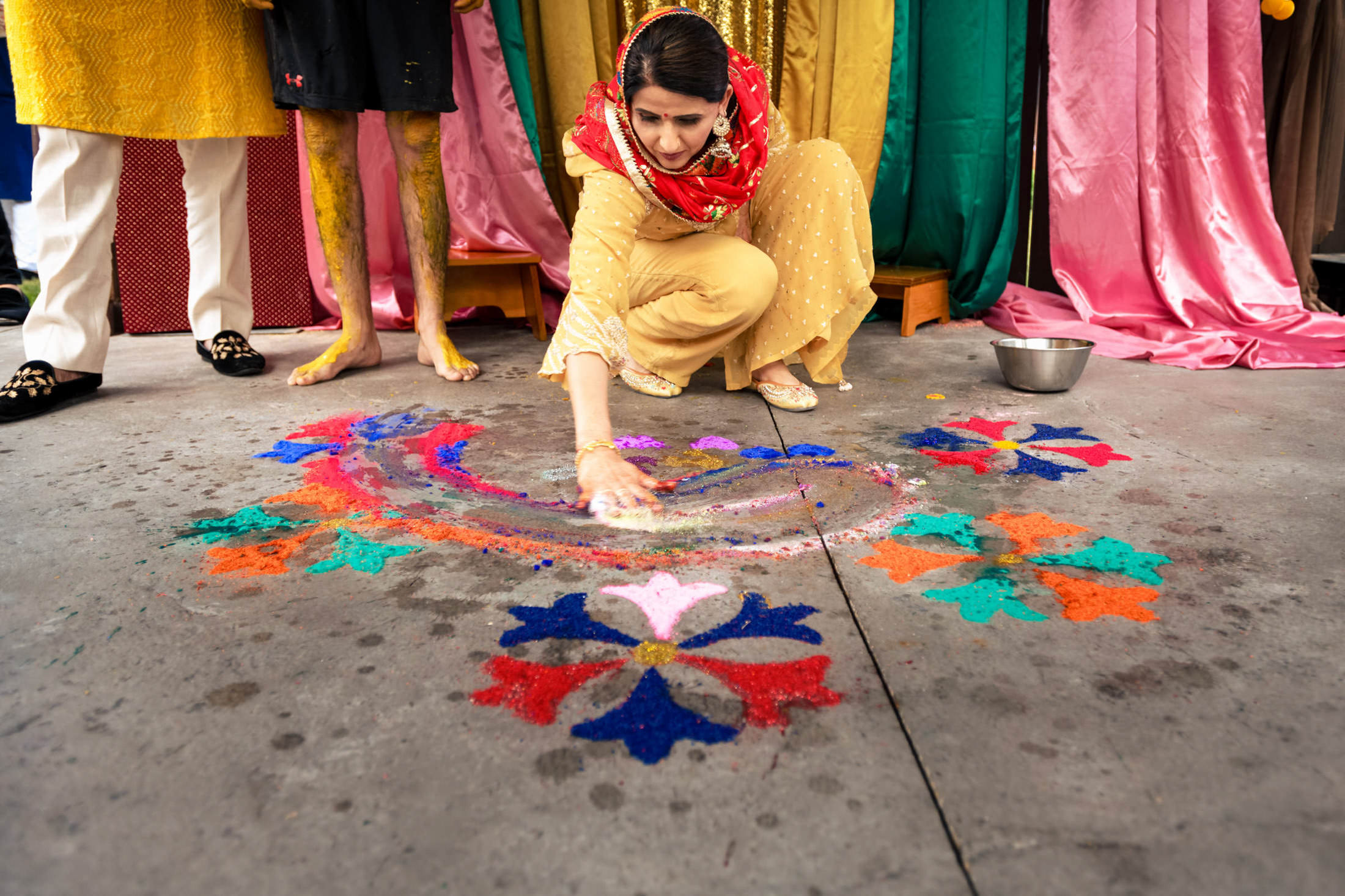 A person in yellow crafts colorful rangoli, adding charm to a Winnipeg wedding setting.