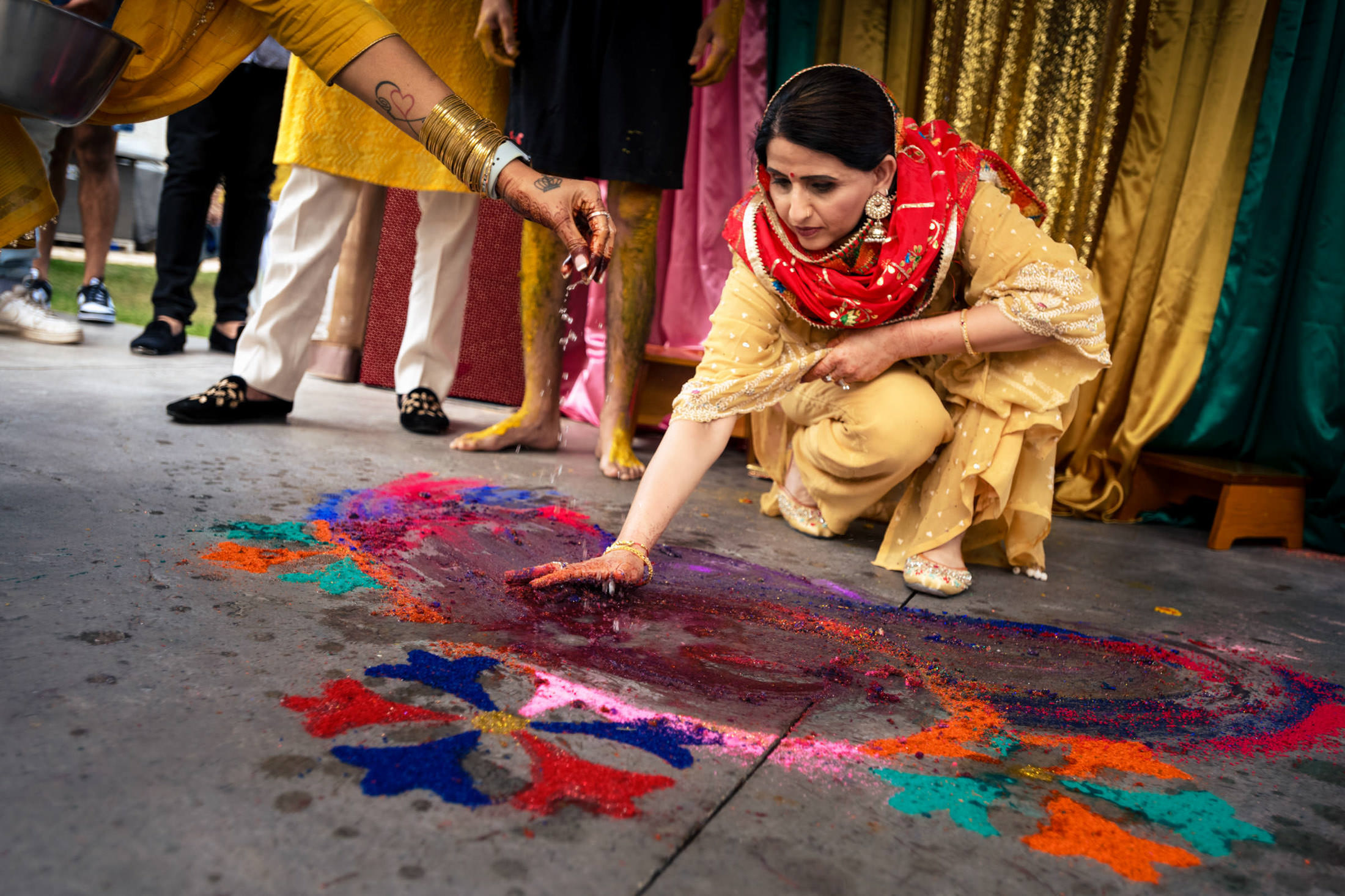 Woman in traditional attire creating colorful Rangoli at a festive Winnipeg wedding.