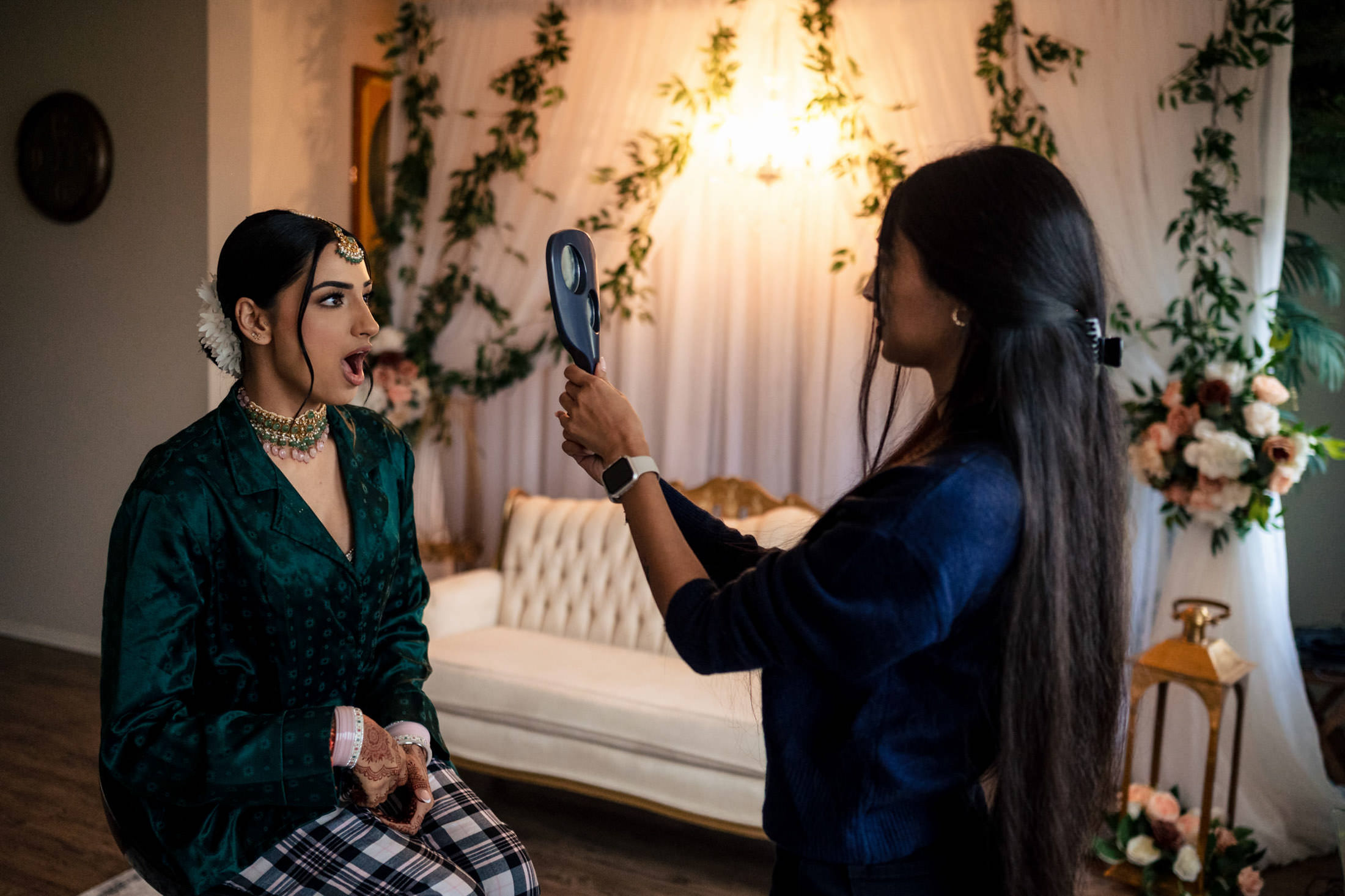 Bride at a Winnipeg wedding gazing into a hand mirror in a decorated room.