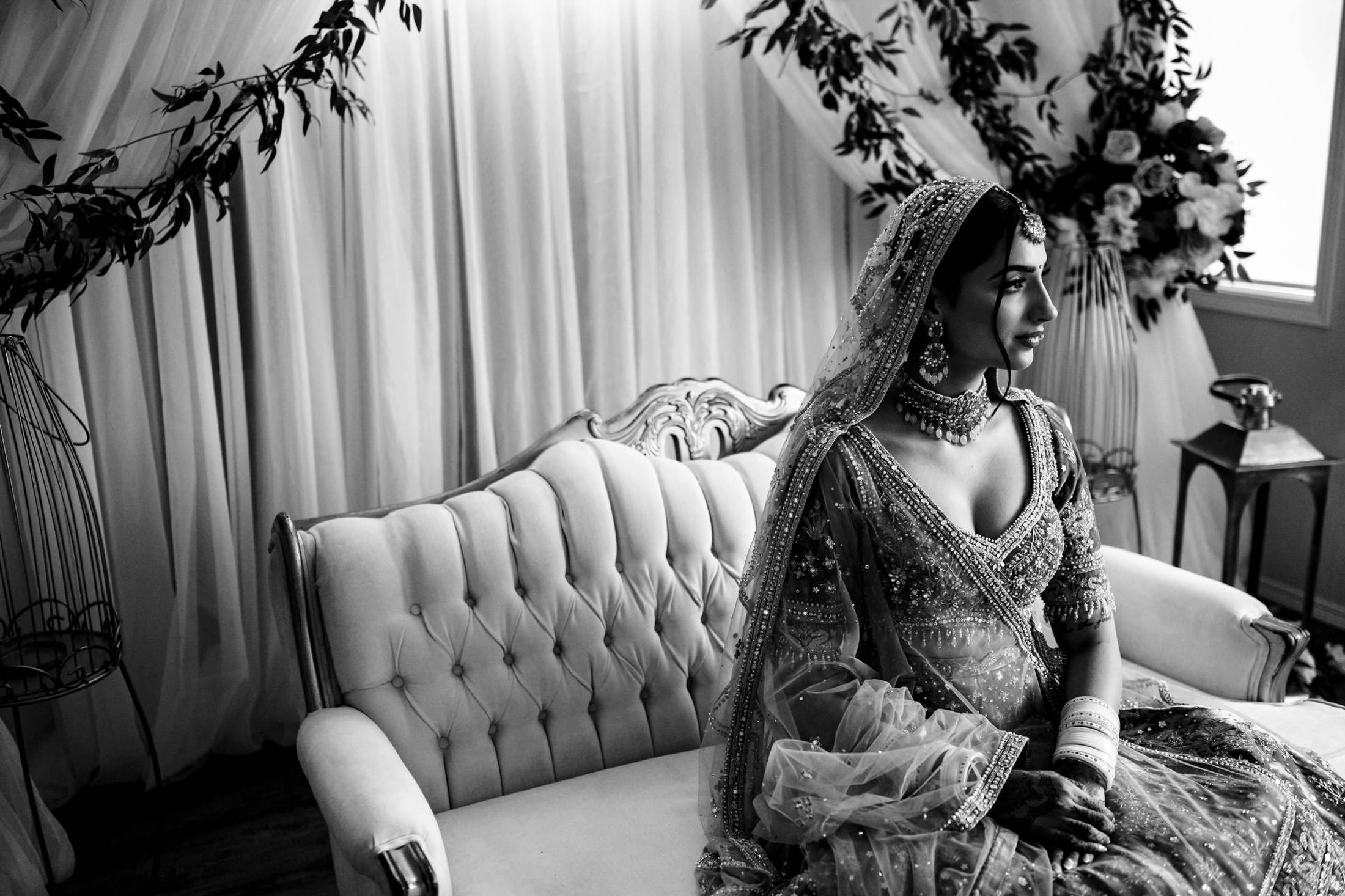 Bride in traditional attire on a sofa, surrounded by floral decor at a Winnipeg wedding.