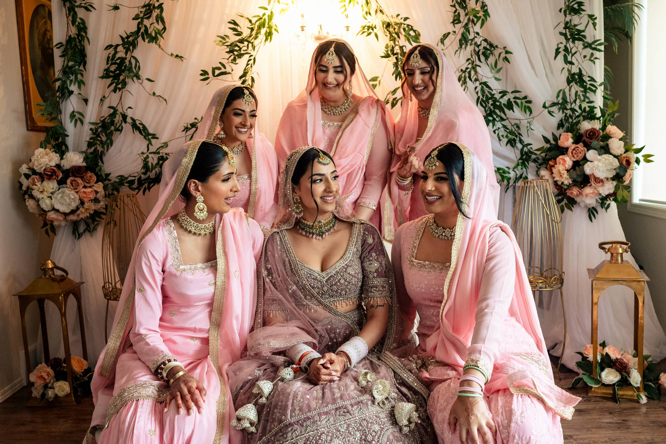 Bride in embroidered gown with bridesmaids in pink, all smiling at a Winnipeg wedding.