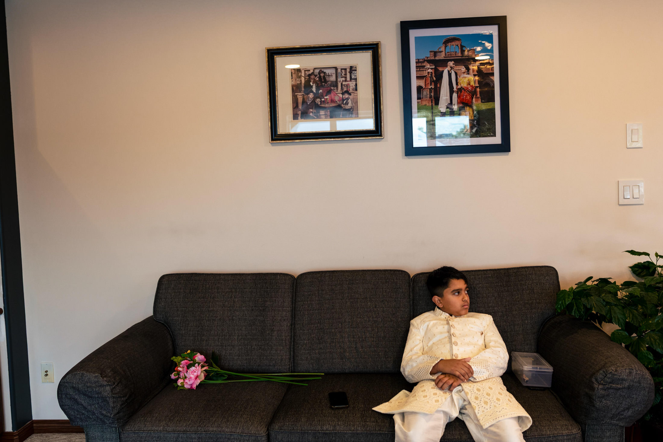 Child in traditional attire sits on couch; Winnipeg wedding photos adorn the wall.