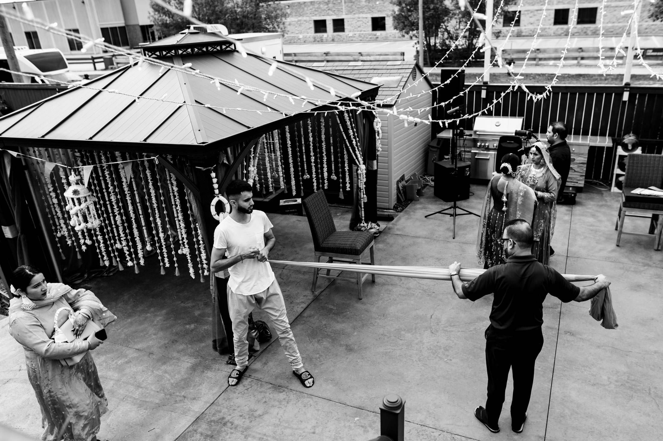 People preparing for a Winnipeg wedding under a decorated gazebo in a backyard.