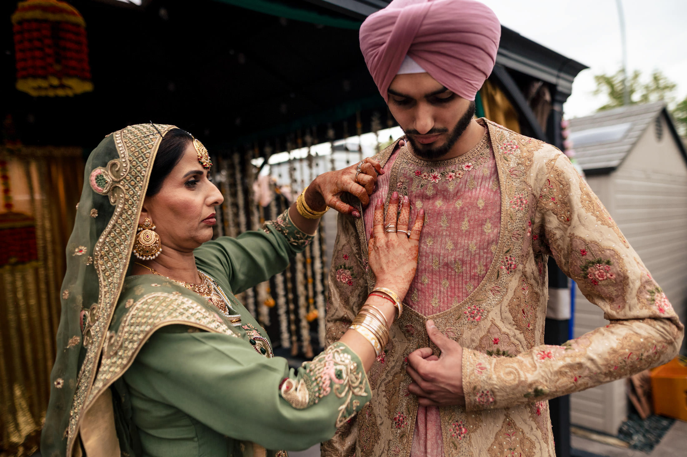 A woman adjusts a young man's ornate outfit at a Winnipeg wedding event.