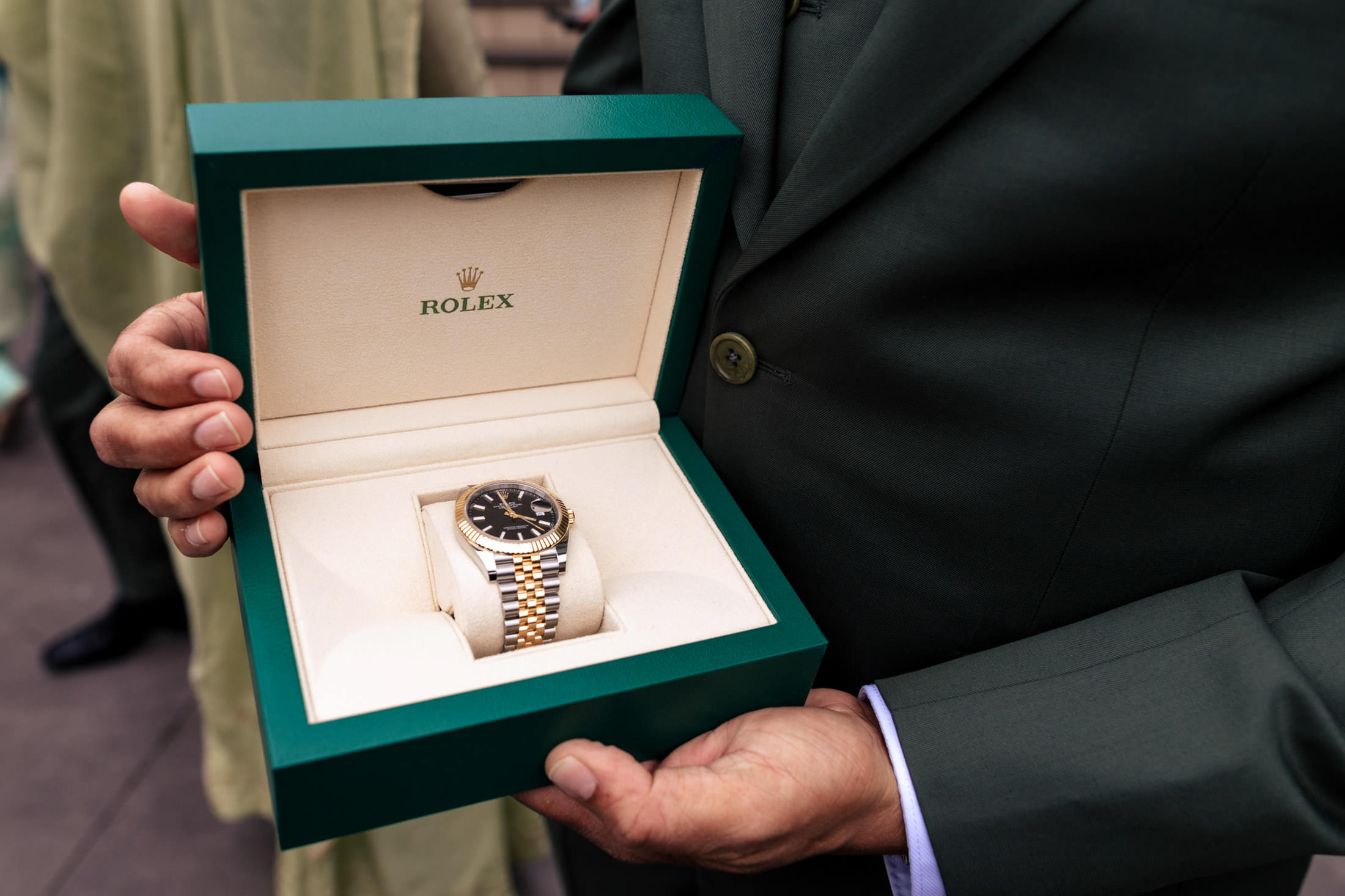 Person holding an open green Rolex box with a two-tone watch inside at a Winnipeg wedding.