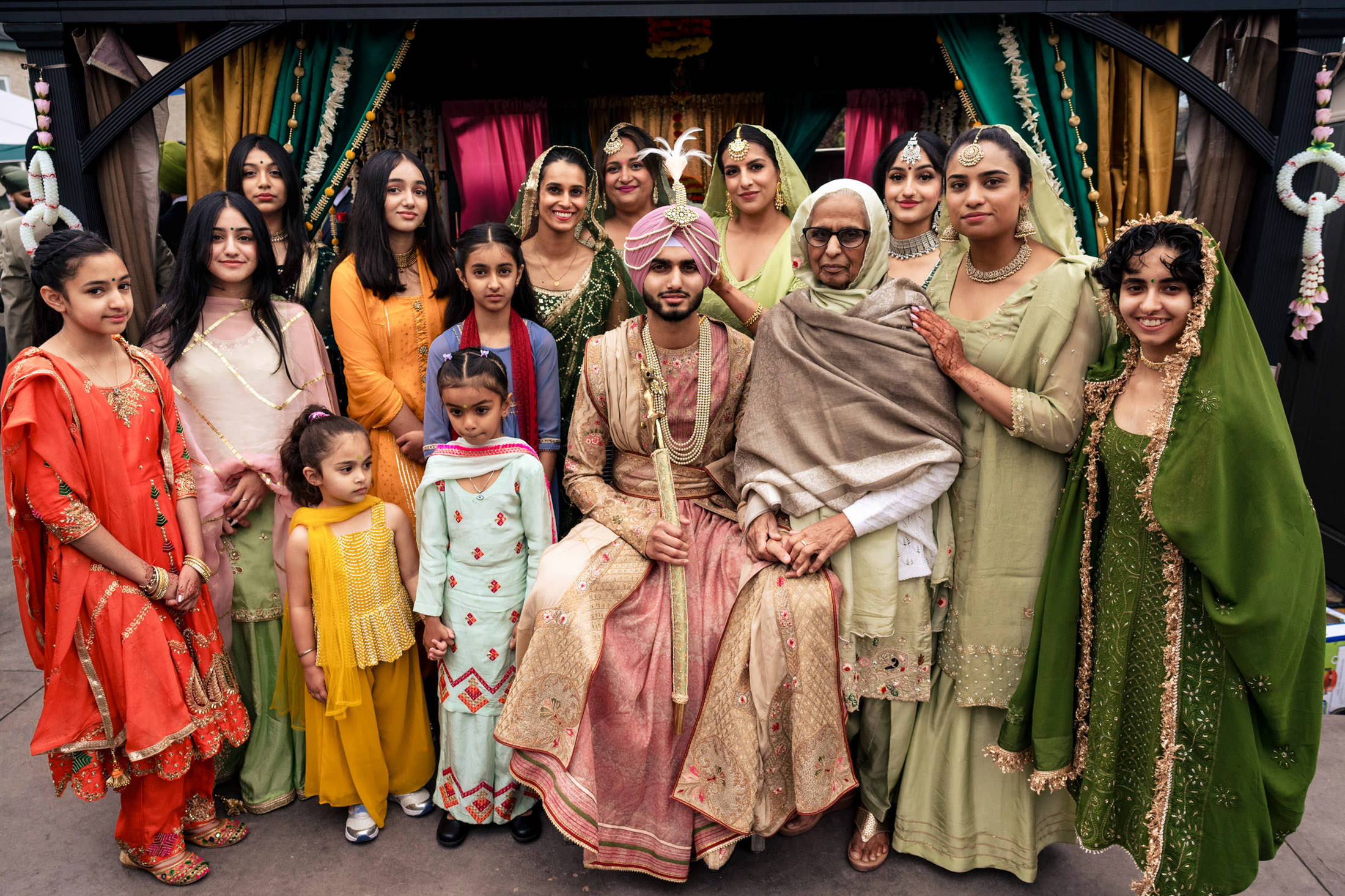 Winnipeg wedding photo of a couple in traditional attire with family in colorful clothing.
