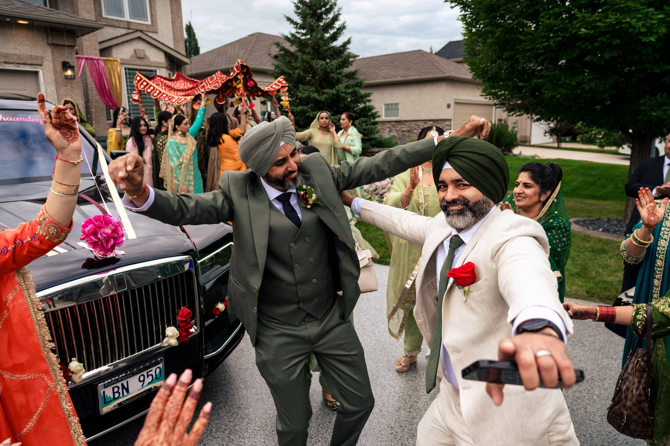 Two men dancing energetically at an outdoor Winnipeg wedding with people gathered around.