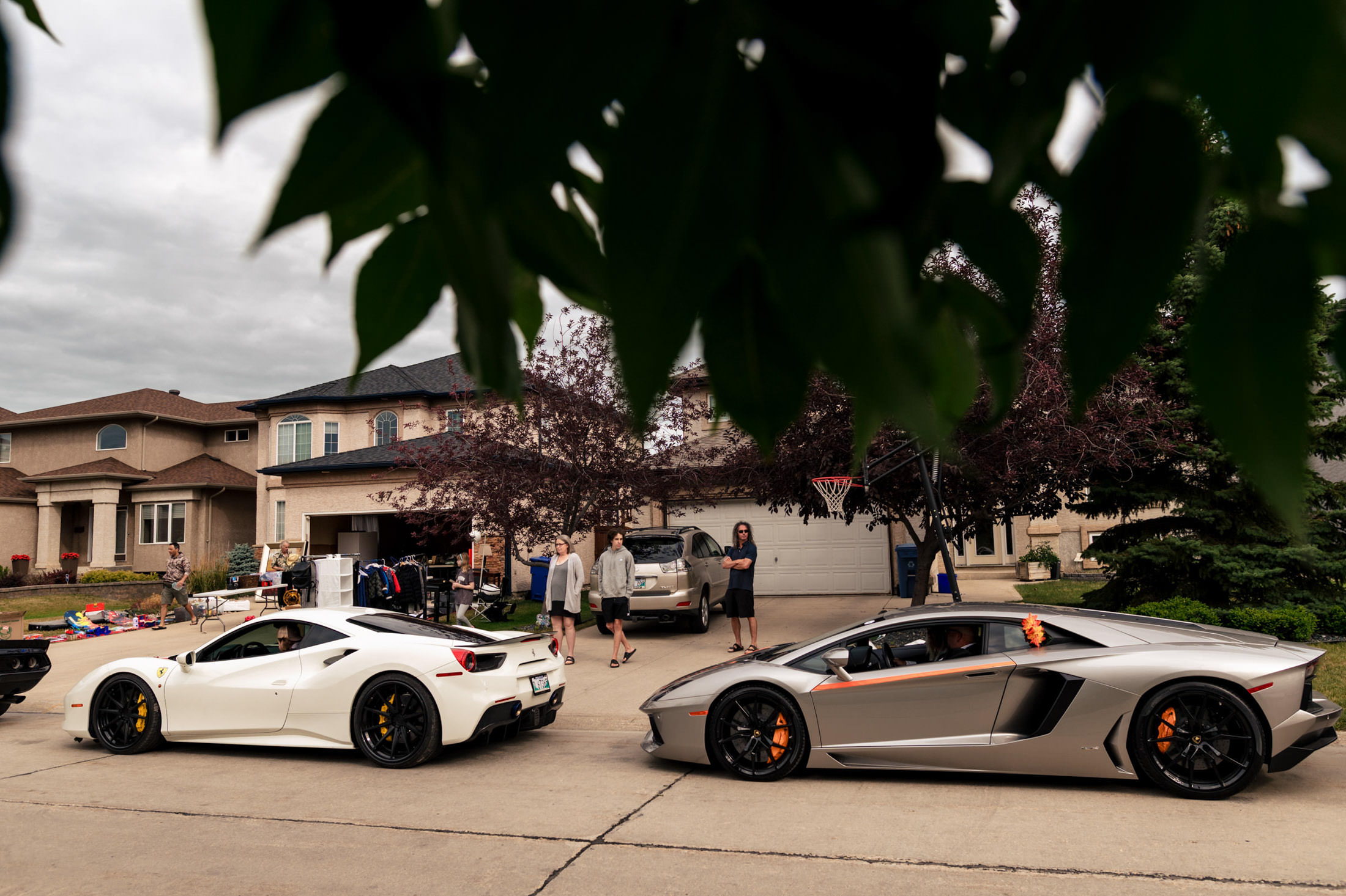 Two luxury sports cars parked nearby a Winnipeg wedding, drawing a gathered crowd.