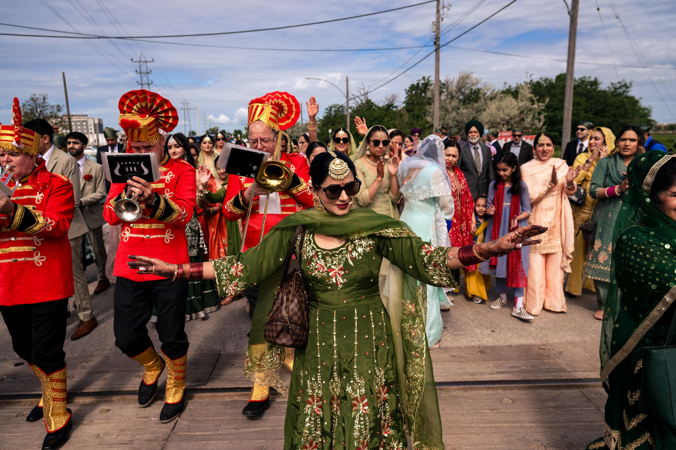 People in vibrant traditional attire celebrate a Winnipeg wedding with a lively marching band.