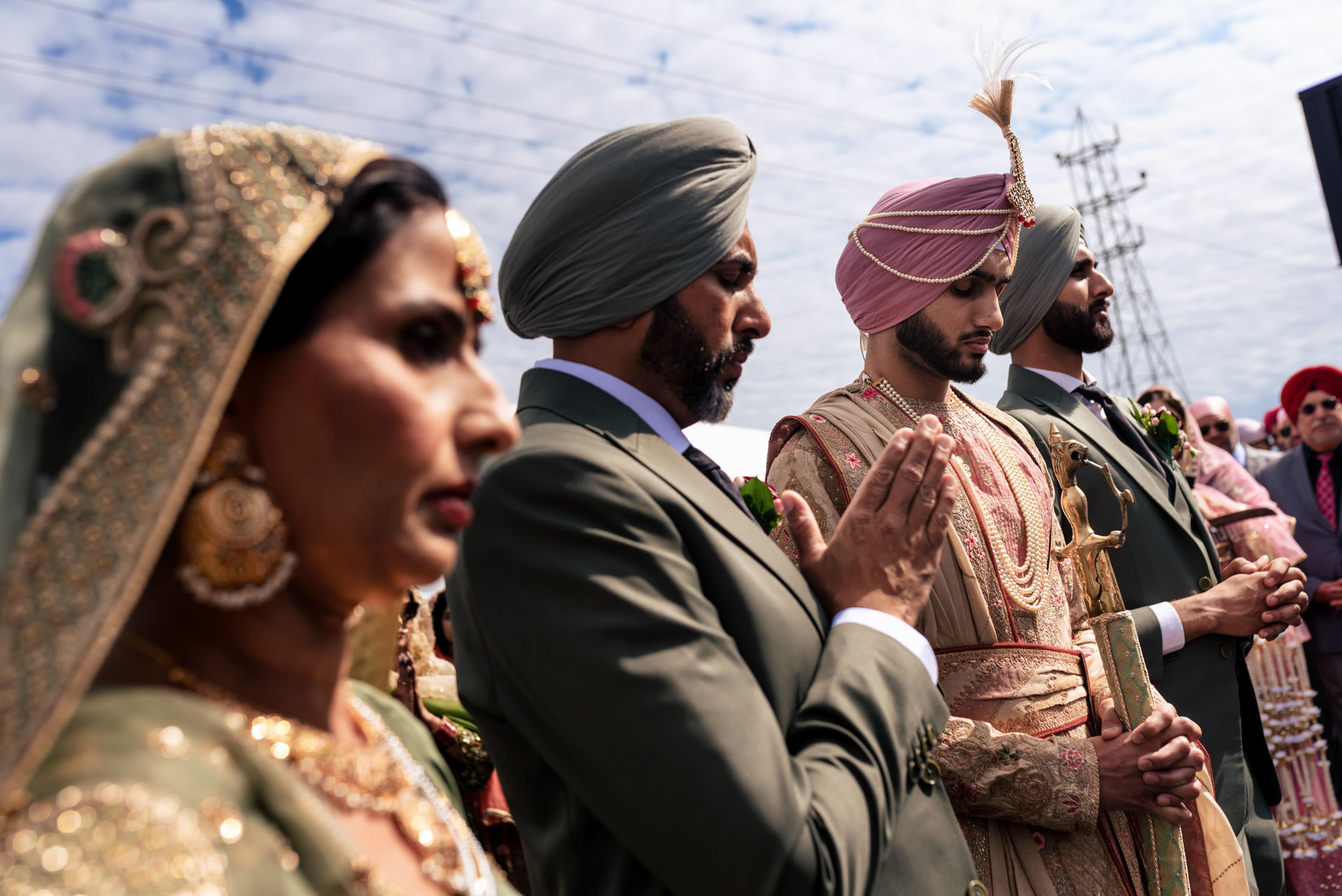 People in traditional Indian attire at a Winnipeg wedding under a cloudy sky.