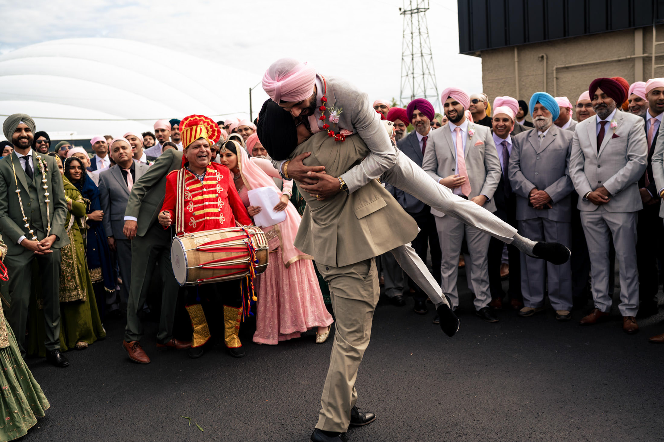 A joyful groom in a pink turban is lifted during a lively Winnipeg wedding celebration.