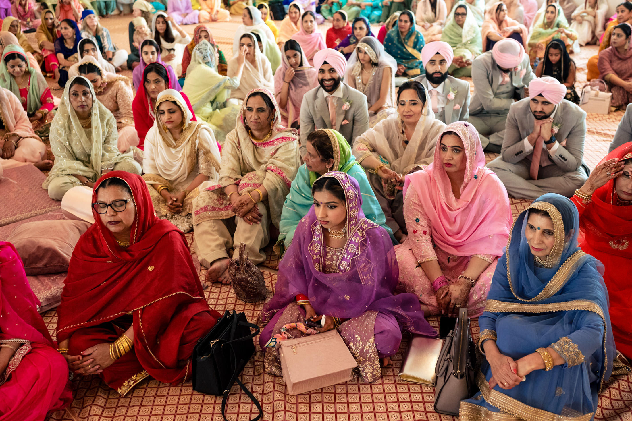 People in colorful traditional attire gather indoors at a Winnipeg wedding.