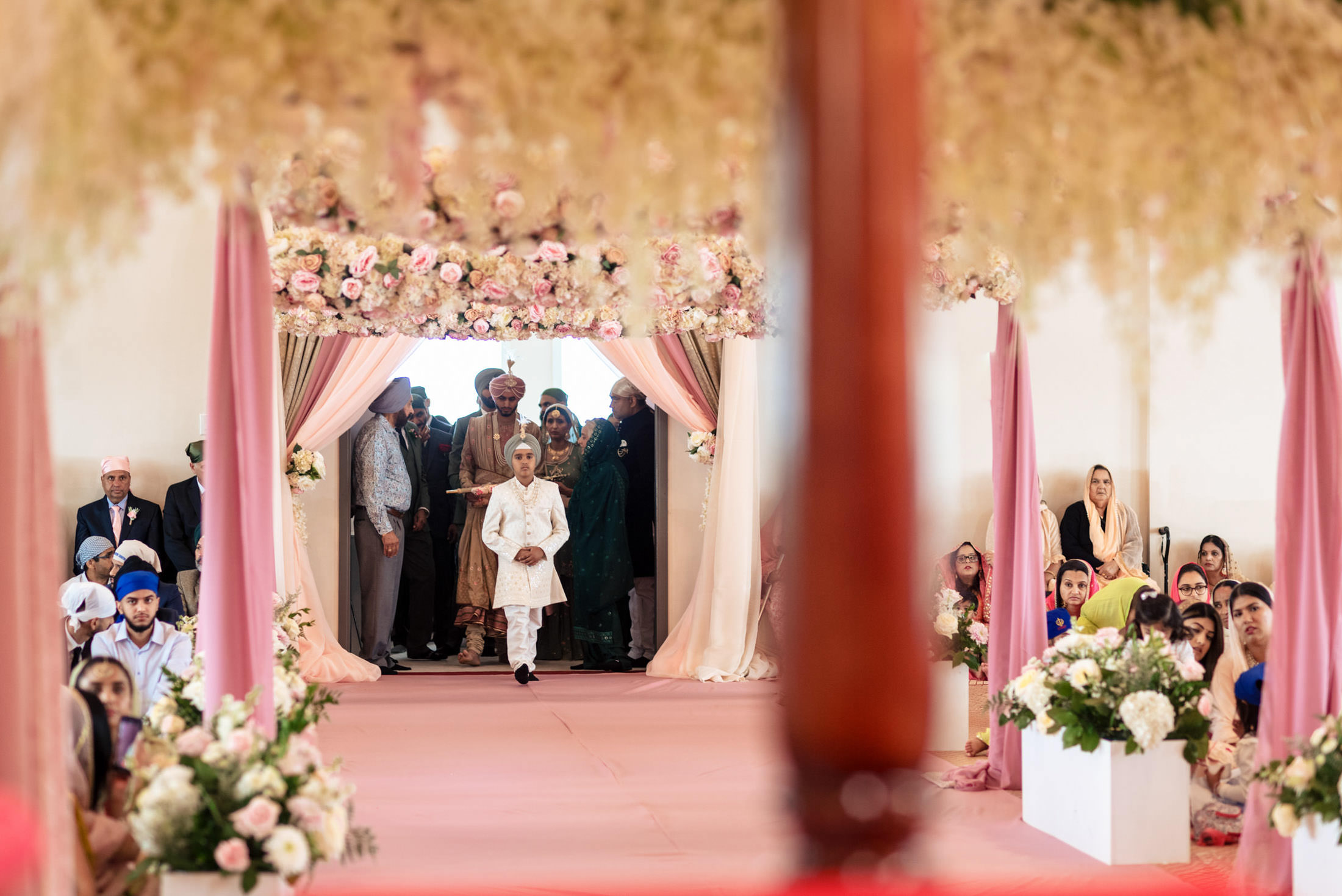 A child walks down an aisle at a Winnipeg wedding, surrounded by guests and floral decor.