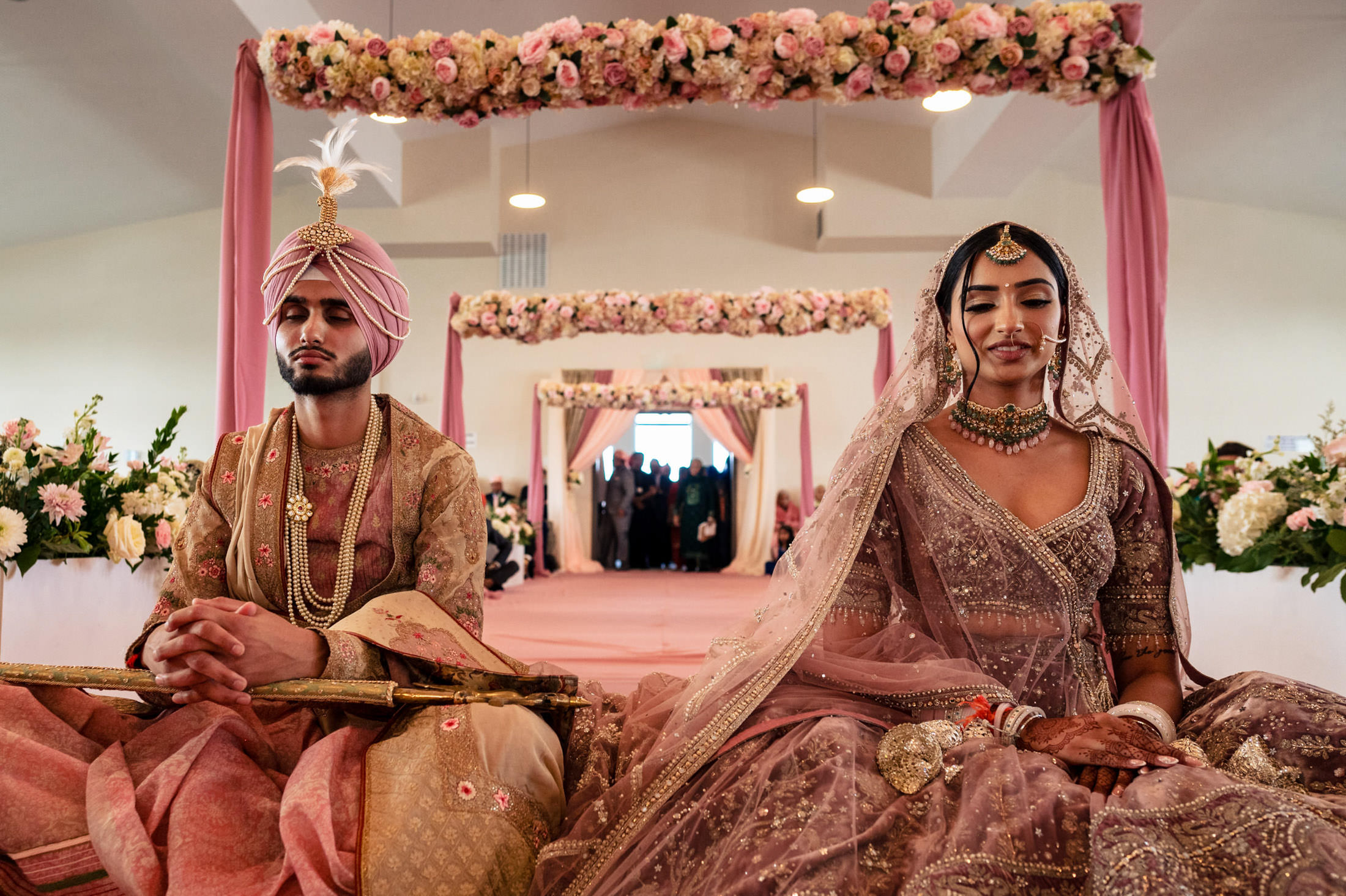 A couple in traditional attire at their Winnipeg wedding, surrounded by floral decorations.