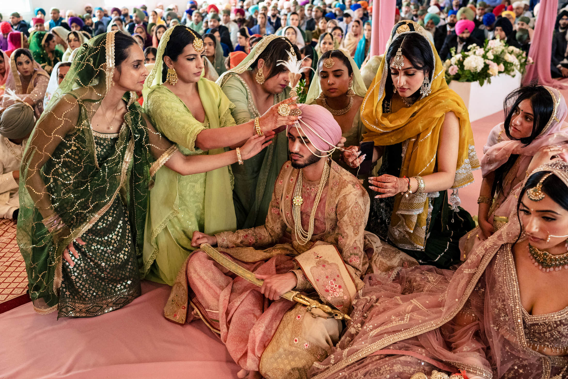A groom in traditional attire prepped by attendants at a vibrant Winnipeg wedding ceremony.
