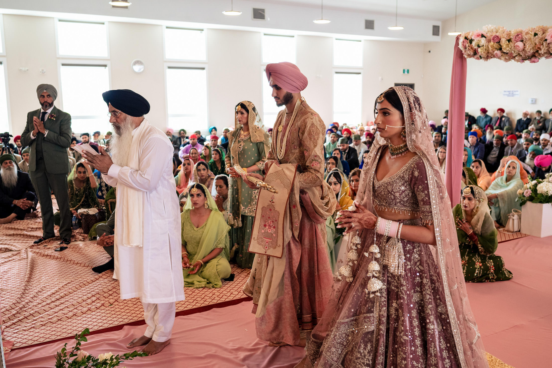 Winnipeg wedding ceremony with a couple and guests seated on the floor in traditional attire.