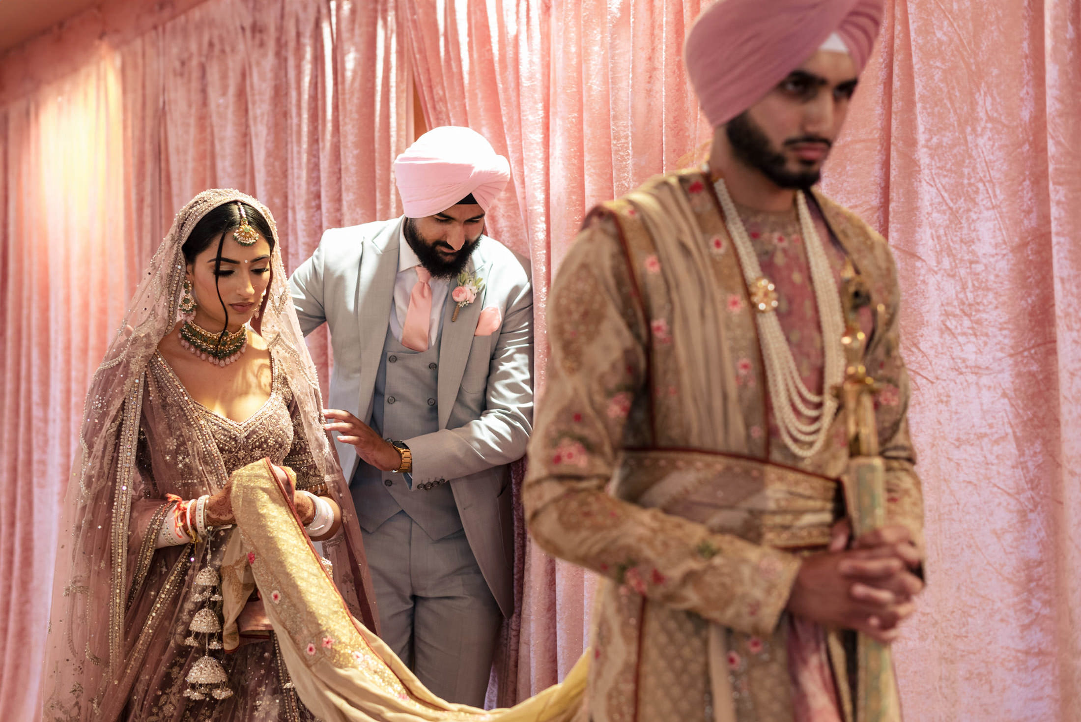 Bride in pink at Winnipeg wedding, groom with them, followed by man in traditional attire.
