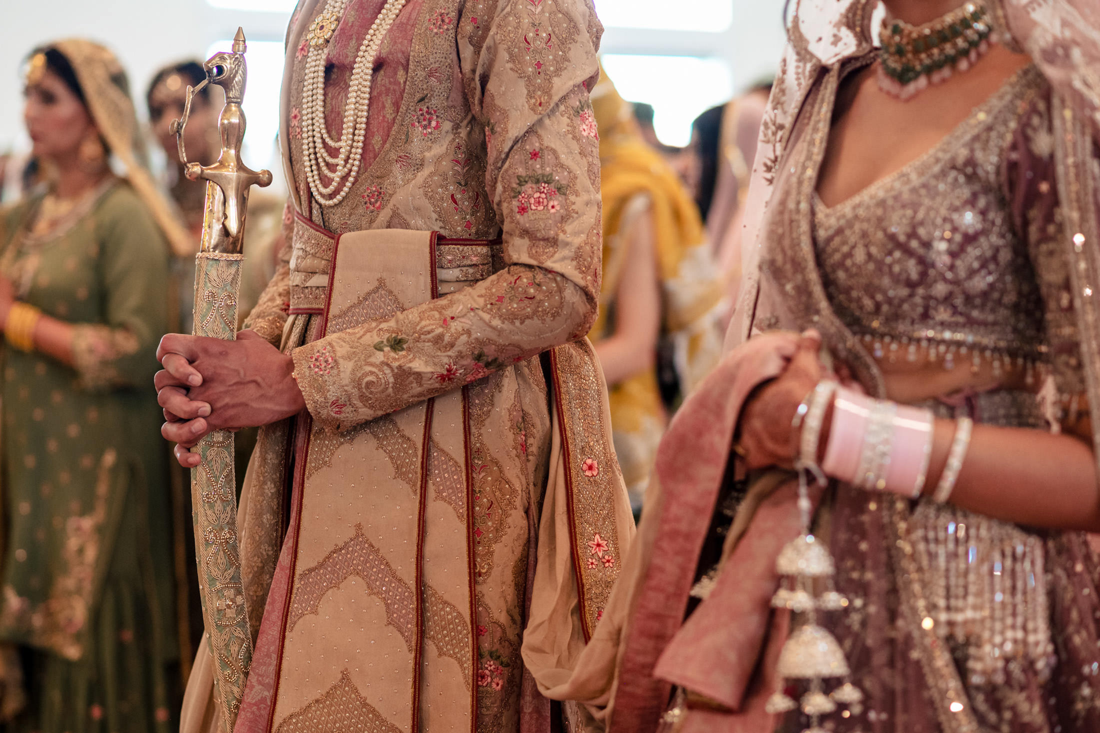 A couple in ornate, traditional attire at a Winnipeg wedding, holding ceremonial items.