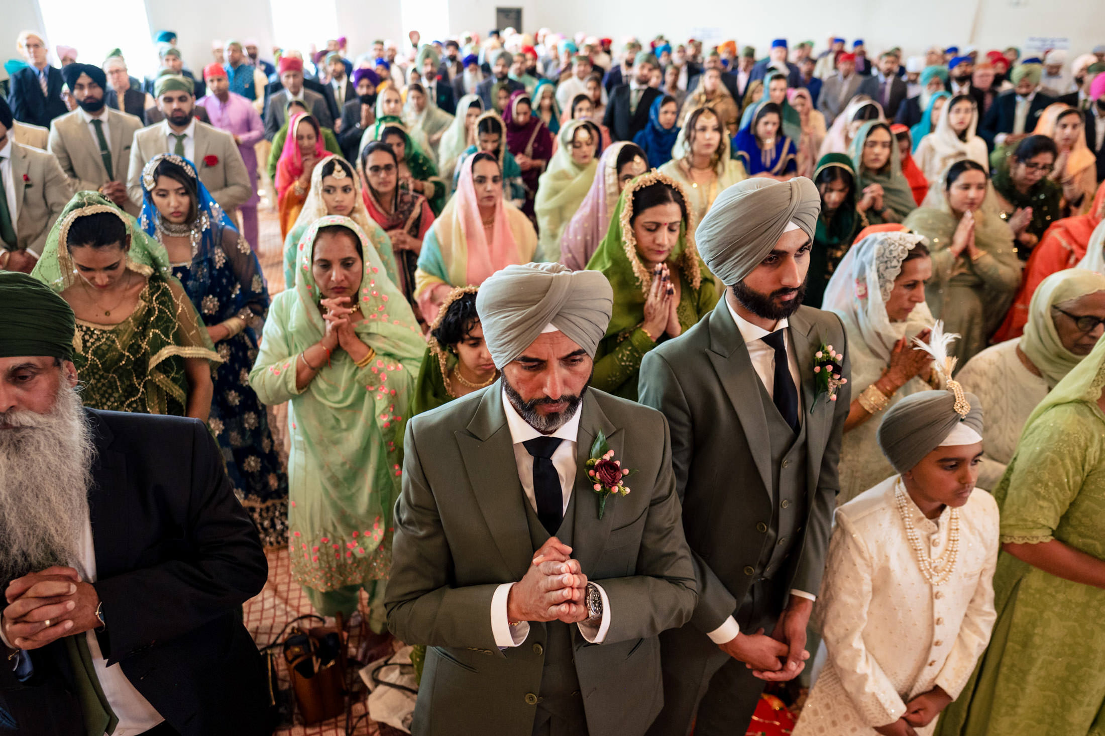 A large group in traditional attire attends a Sikh ceremony at a Winnipeg wedding.