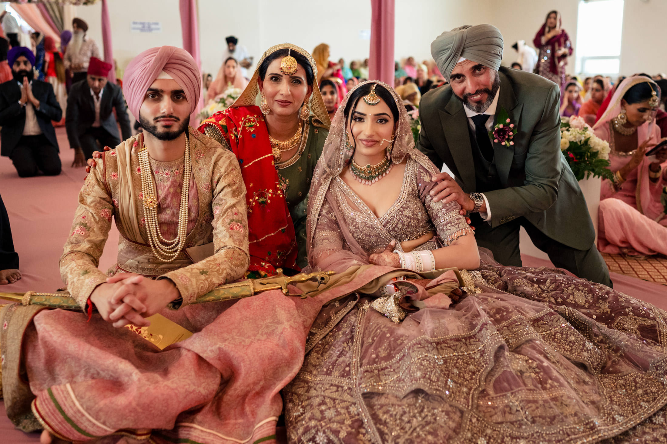Wedding couple sitting with family in traditional attire at their Winnipeg wedding.
