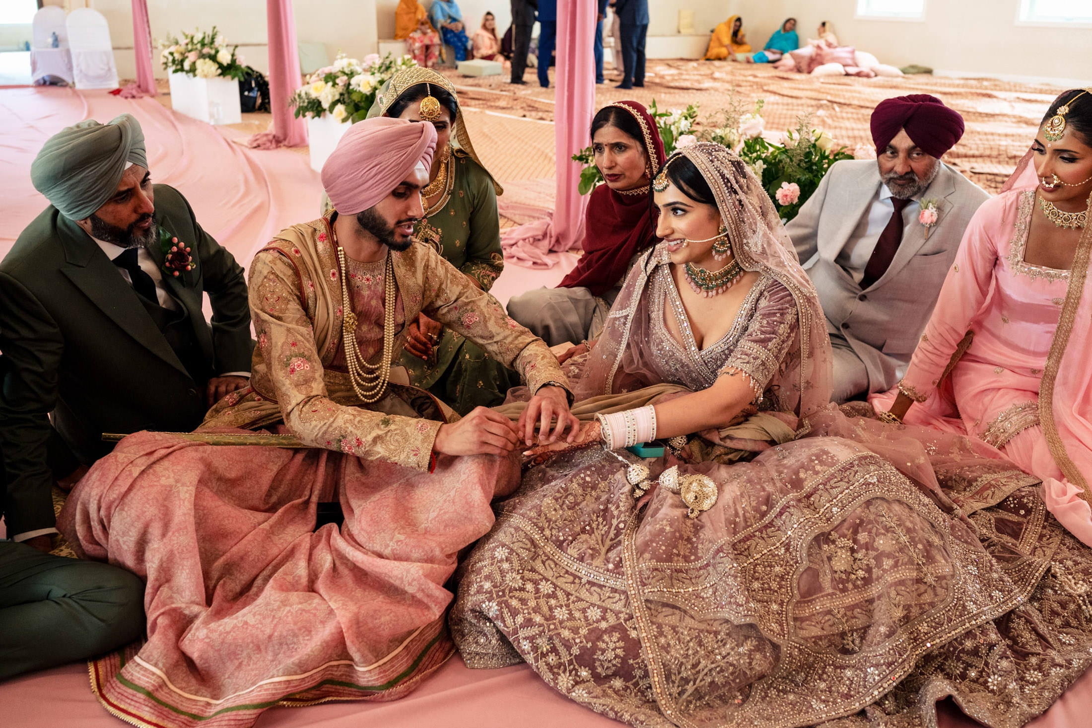 Couple in traditional attire at a Winnipeg Sikh wedding, surrounded by family and friends.