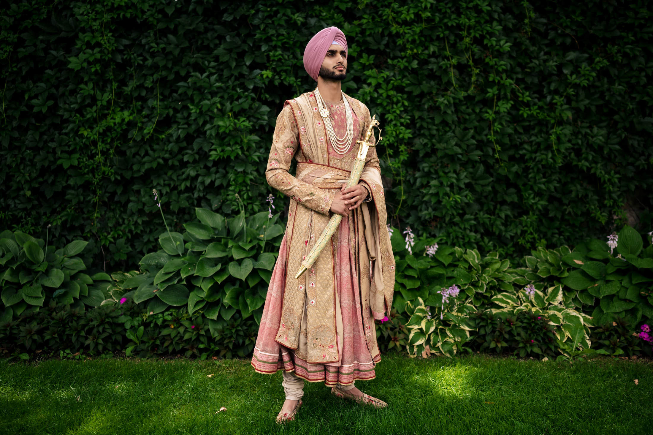 Person outdoors in traditional attire and turban, holding a sword at a Winnipeg wedding.