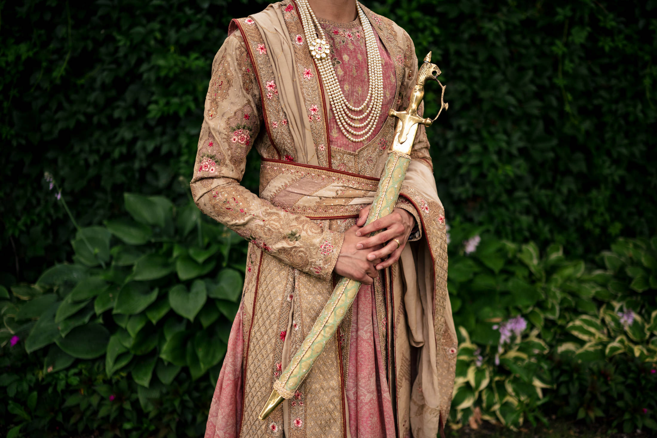 Individual in ornate traditional attire holding a decorative sword at a Winnipeg wedding.