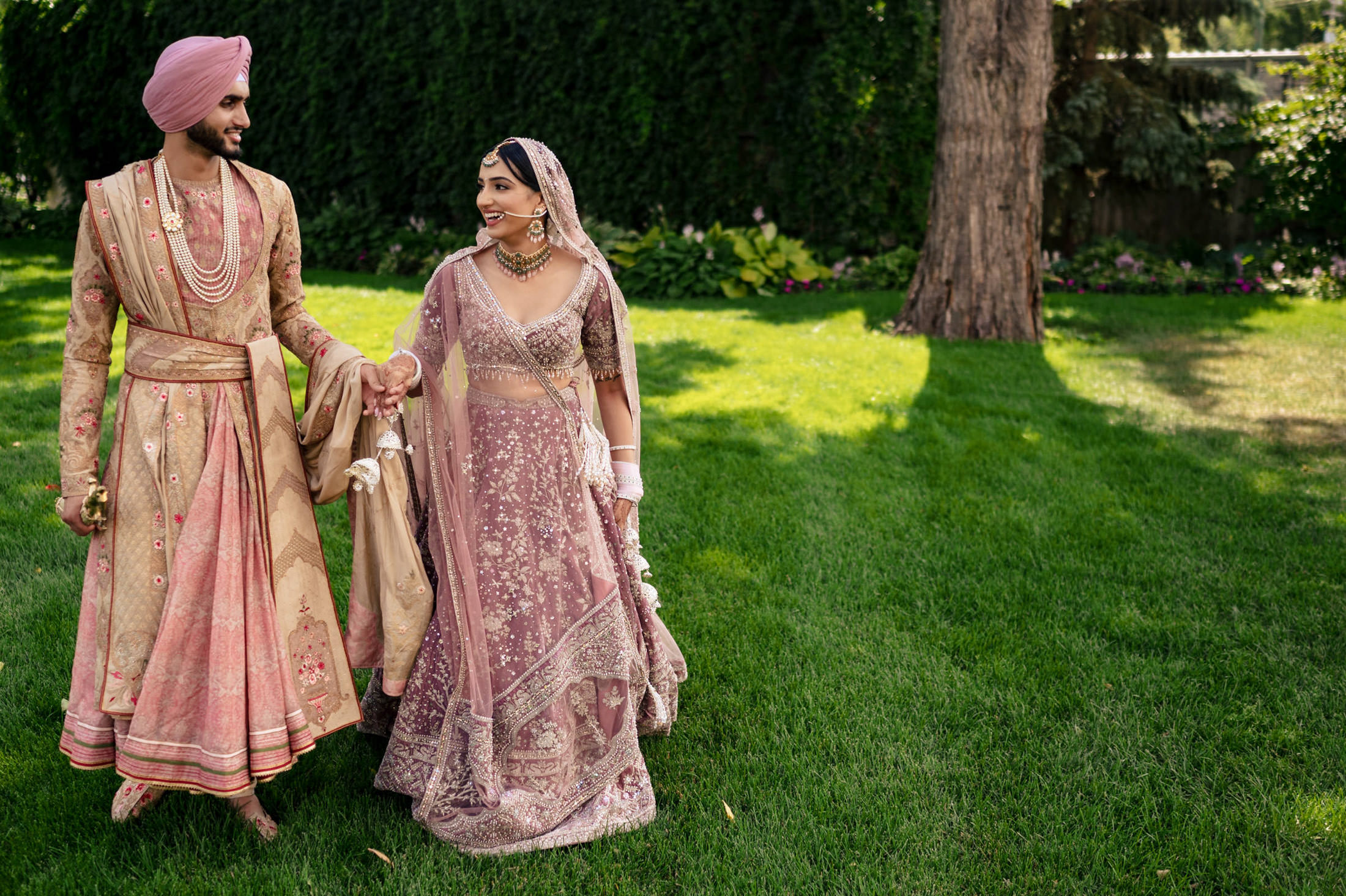 Couple in traditional attire smiling and holding hands at a Winnipeg wedding.