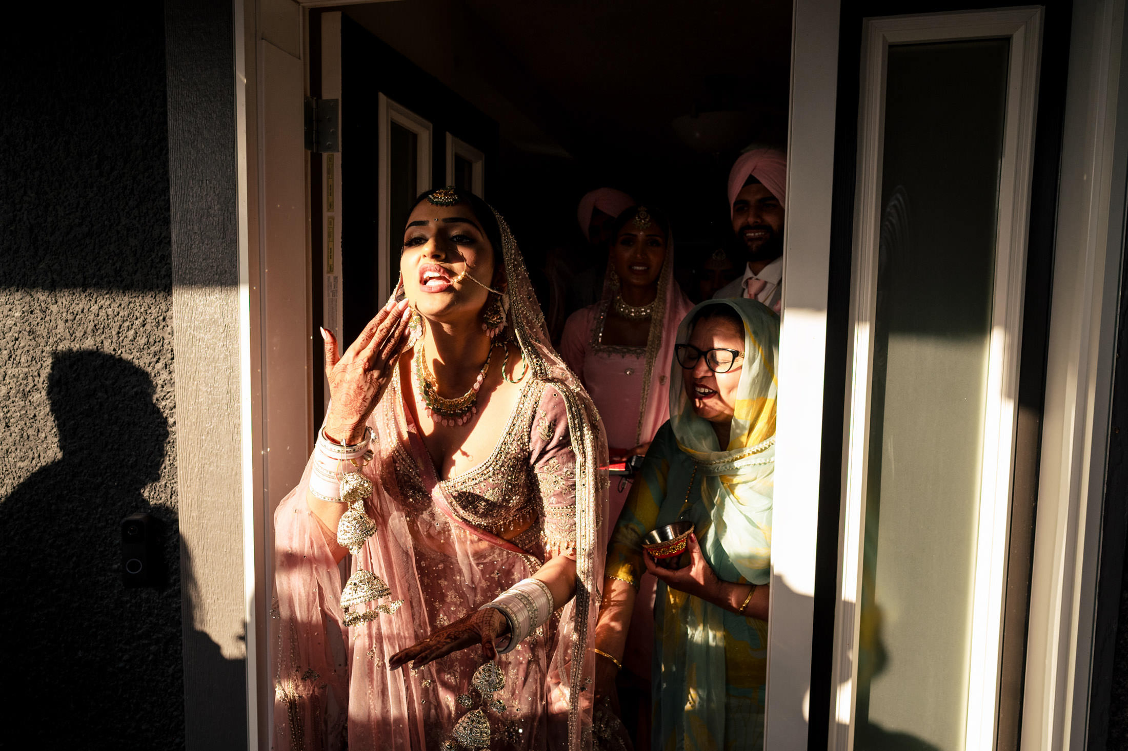 Bride in pink attire exiting, surrounded by smiling family at Winnipeg wedding.