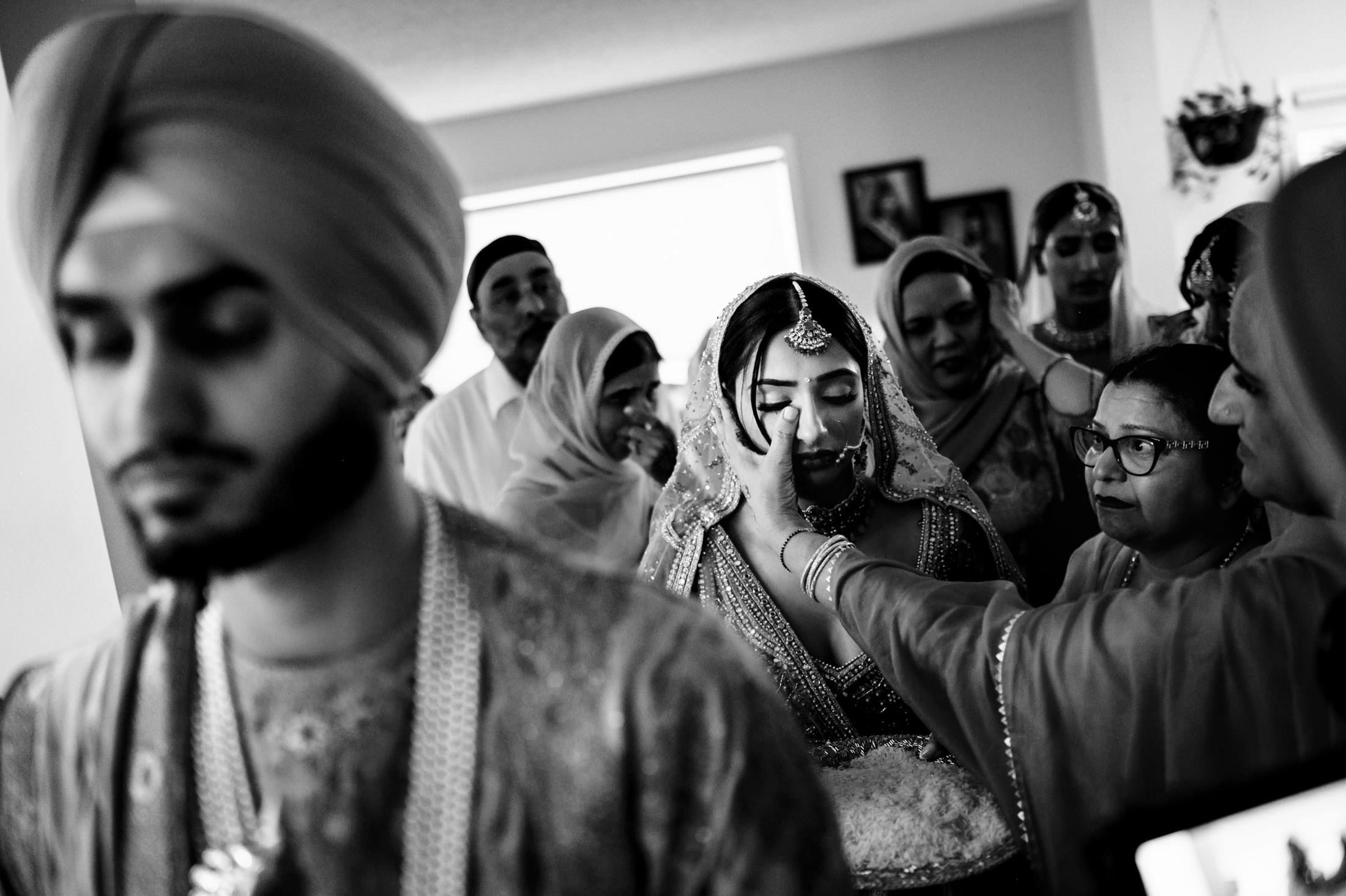Bride in traditional attire, surrounded by family at a Winnipeg wedding in an emotional moment.
