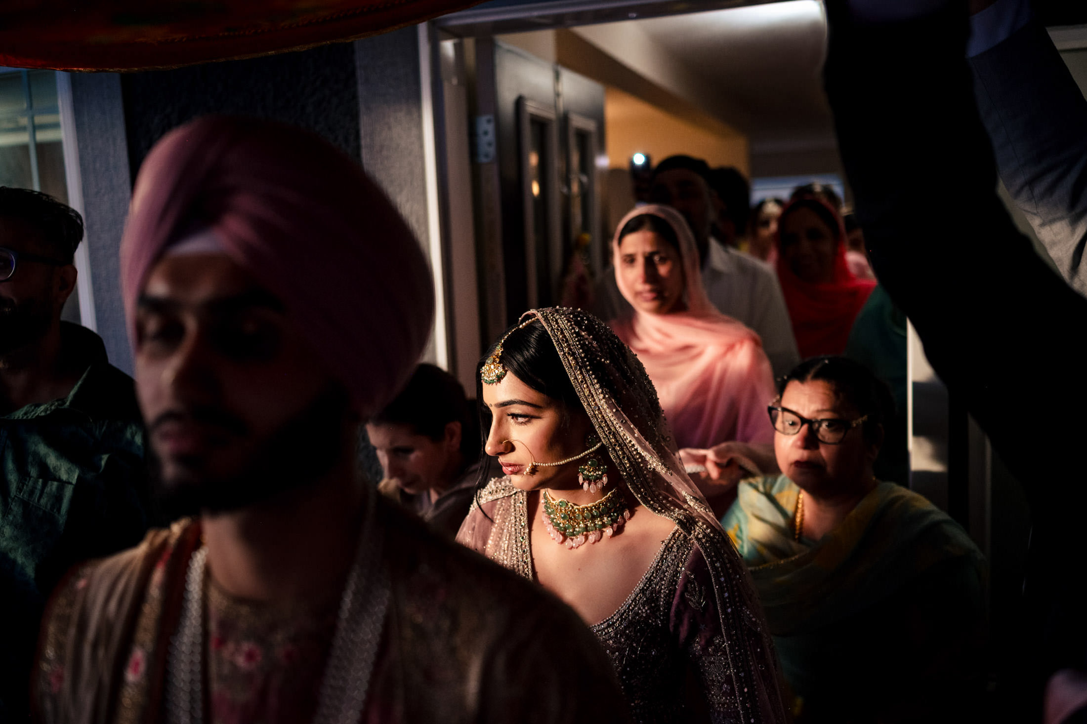 Bride in traditional attire with a group, captured at a dimly lit Winnipeg wedding.