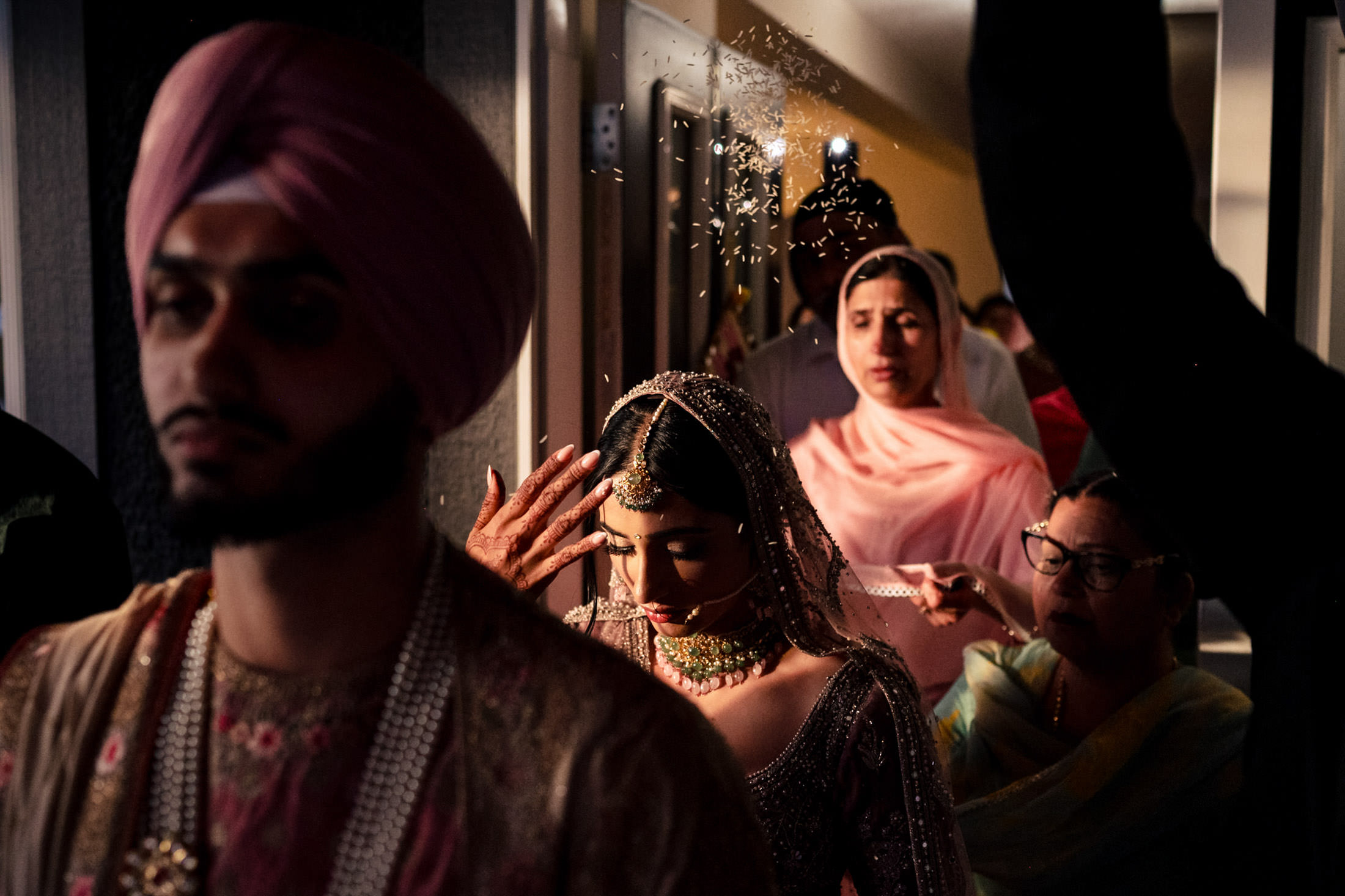Bride in traditional attire with family at a Winnipeg wedding, rice being thrown in the background.
