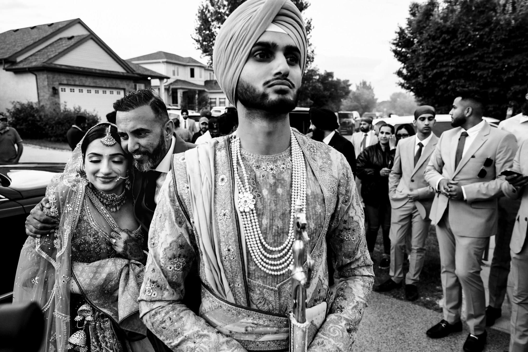 Groom in traditional attire with bride and guests at a Winnipeg wedding outdoor celebration.