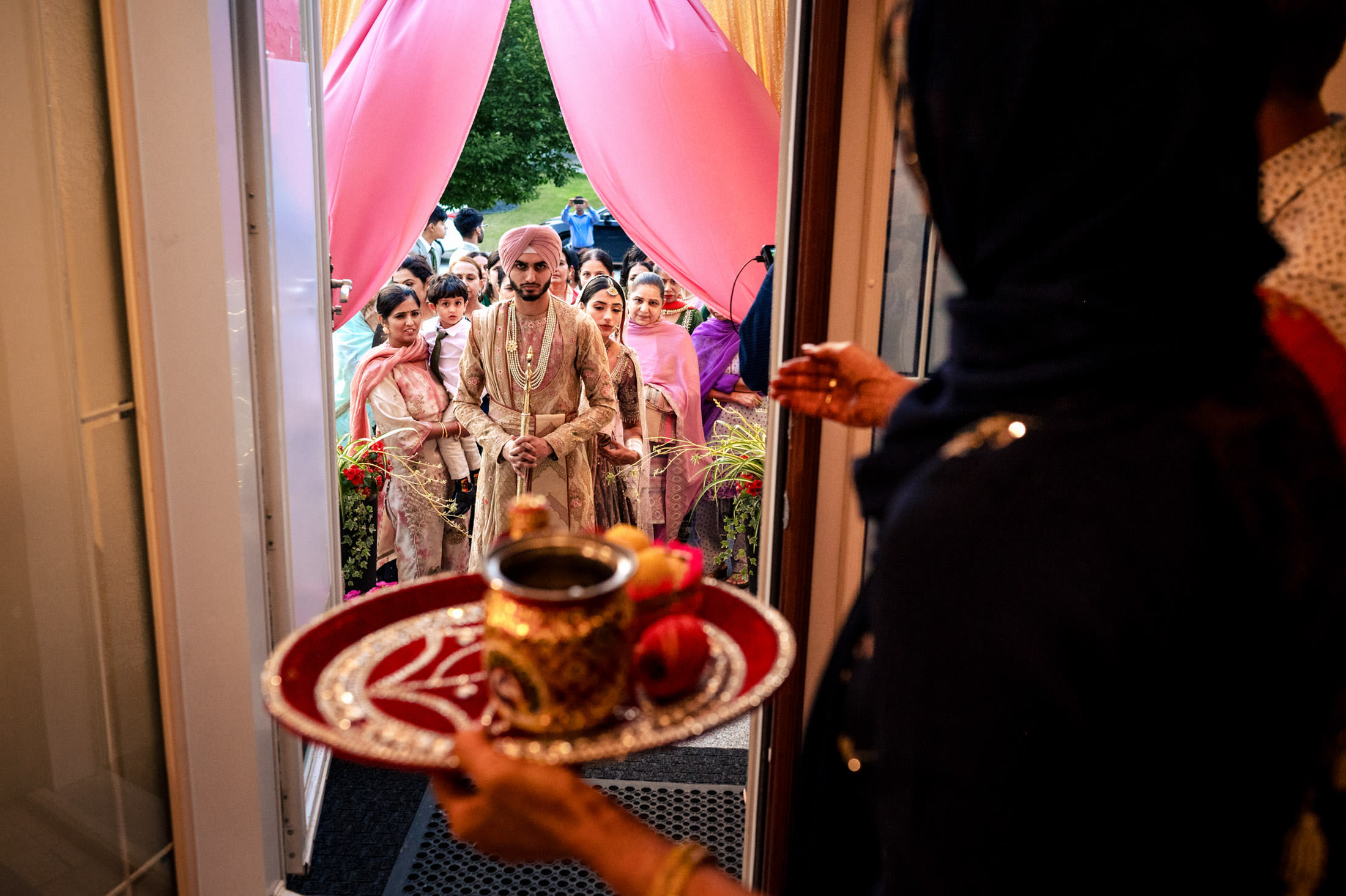 A groom arrives at a Winnipeg wedding doorway, welcomed with a tray and drinks.
