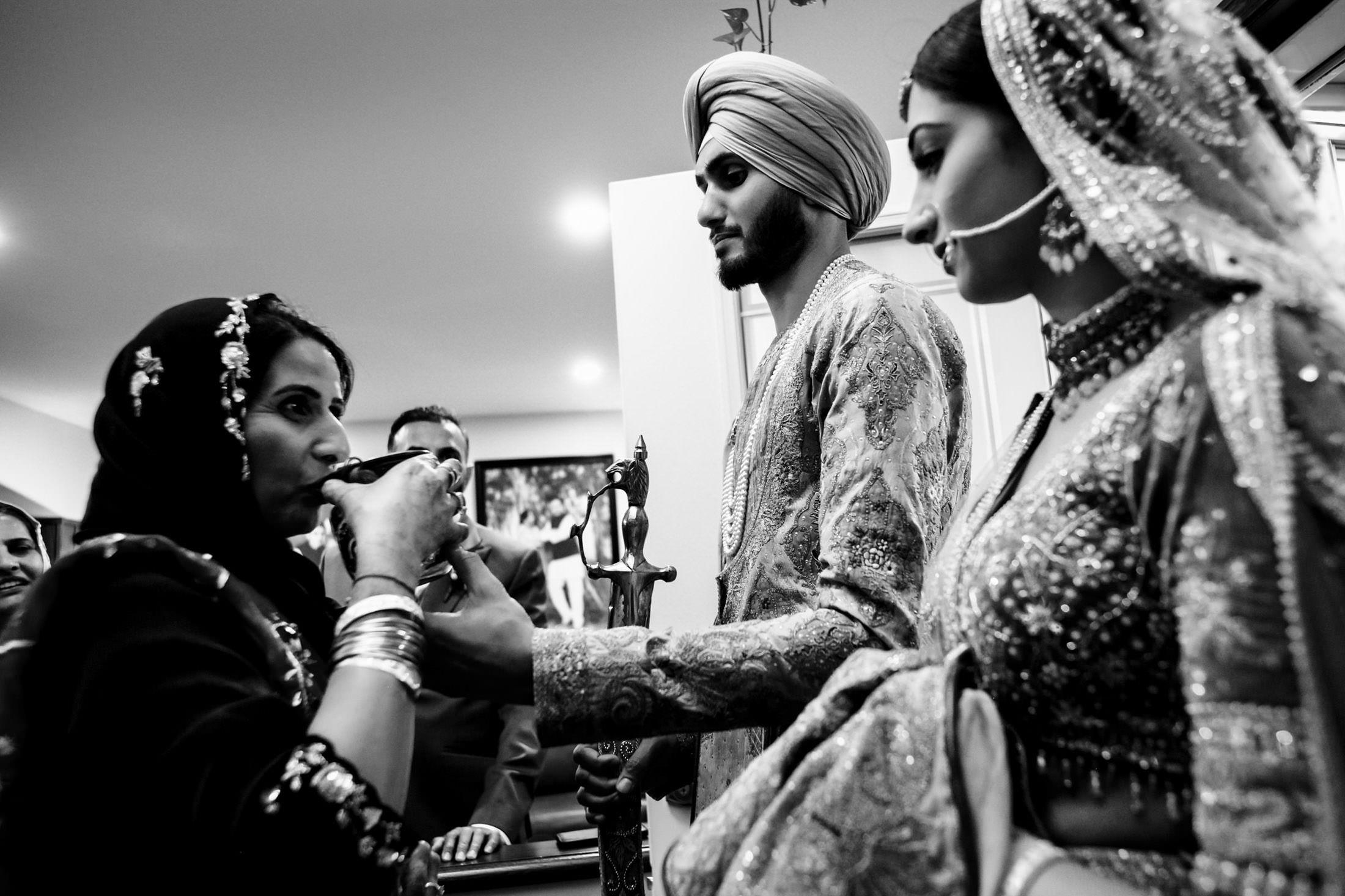 A couple in traditional attire join an older woman for a Winnipeg wedding ritual.