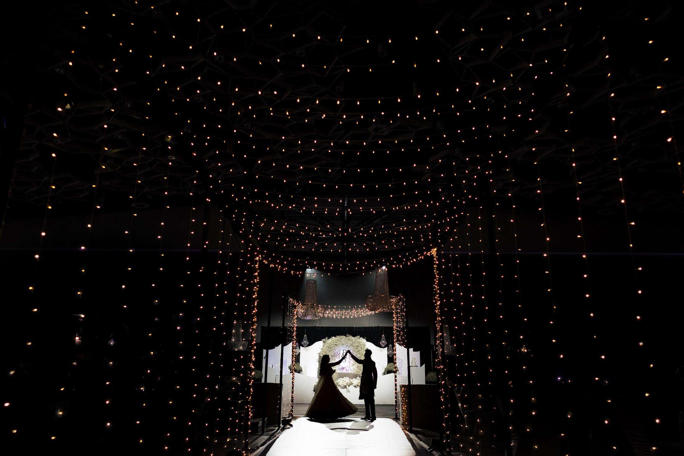Silhouetted couple dancing under string lights at an elegant Winnipeg wedding.