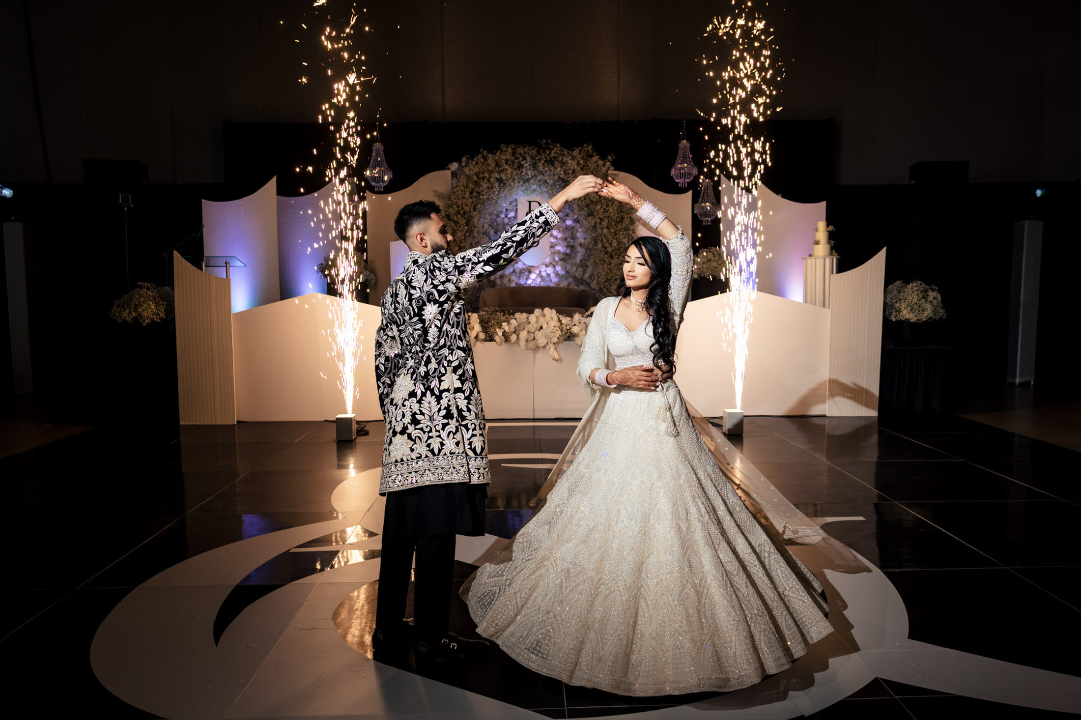 Couple dancing at their Winnipeg wedding, surrounded by fireworks and elegant floral decor.